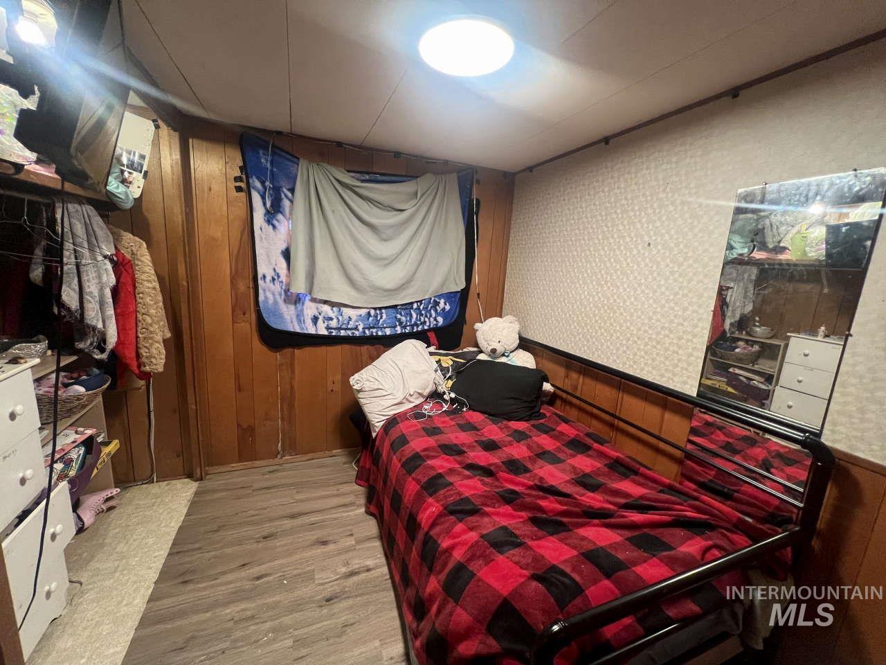 Bedroom featuring wooden walls and wood finished floors
