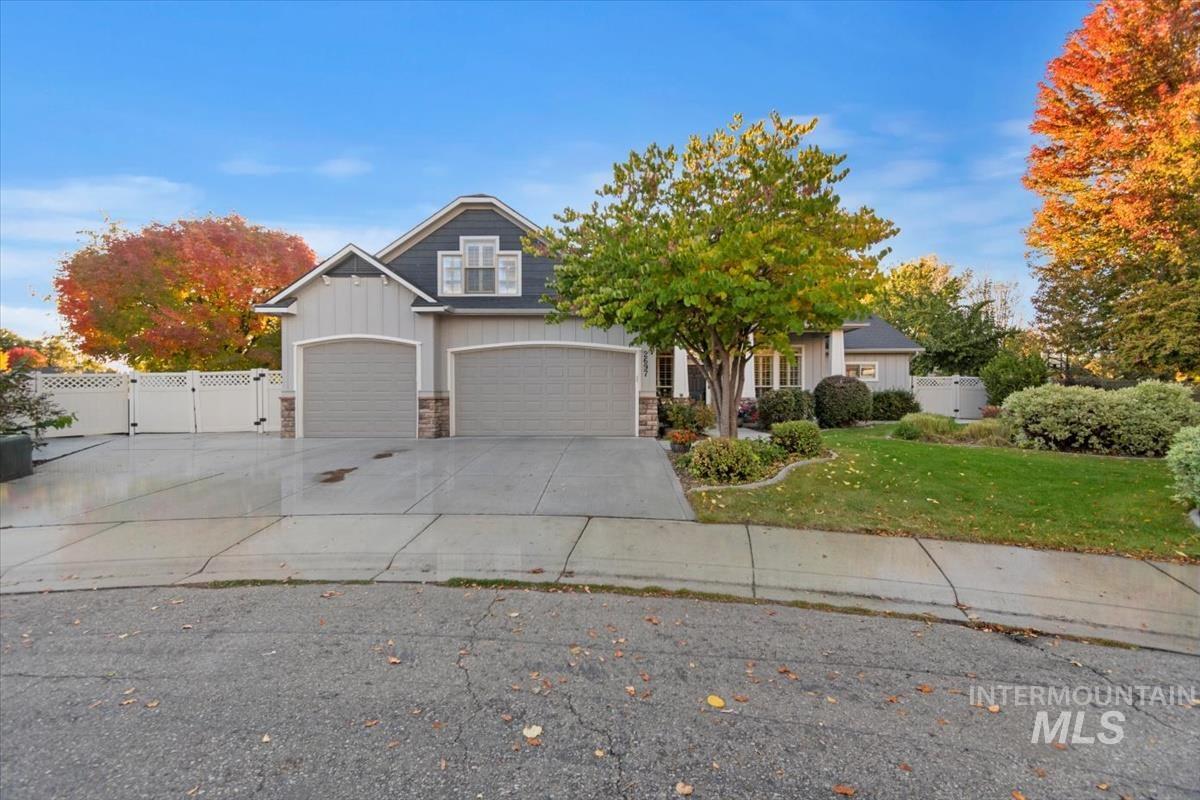 View of front of house with stone siding, concrete driveway, a gate, and board and batten siding