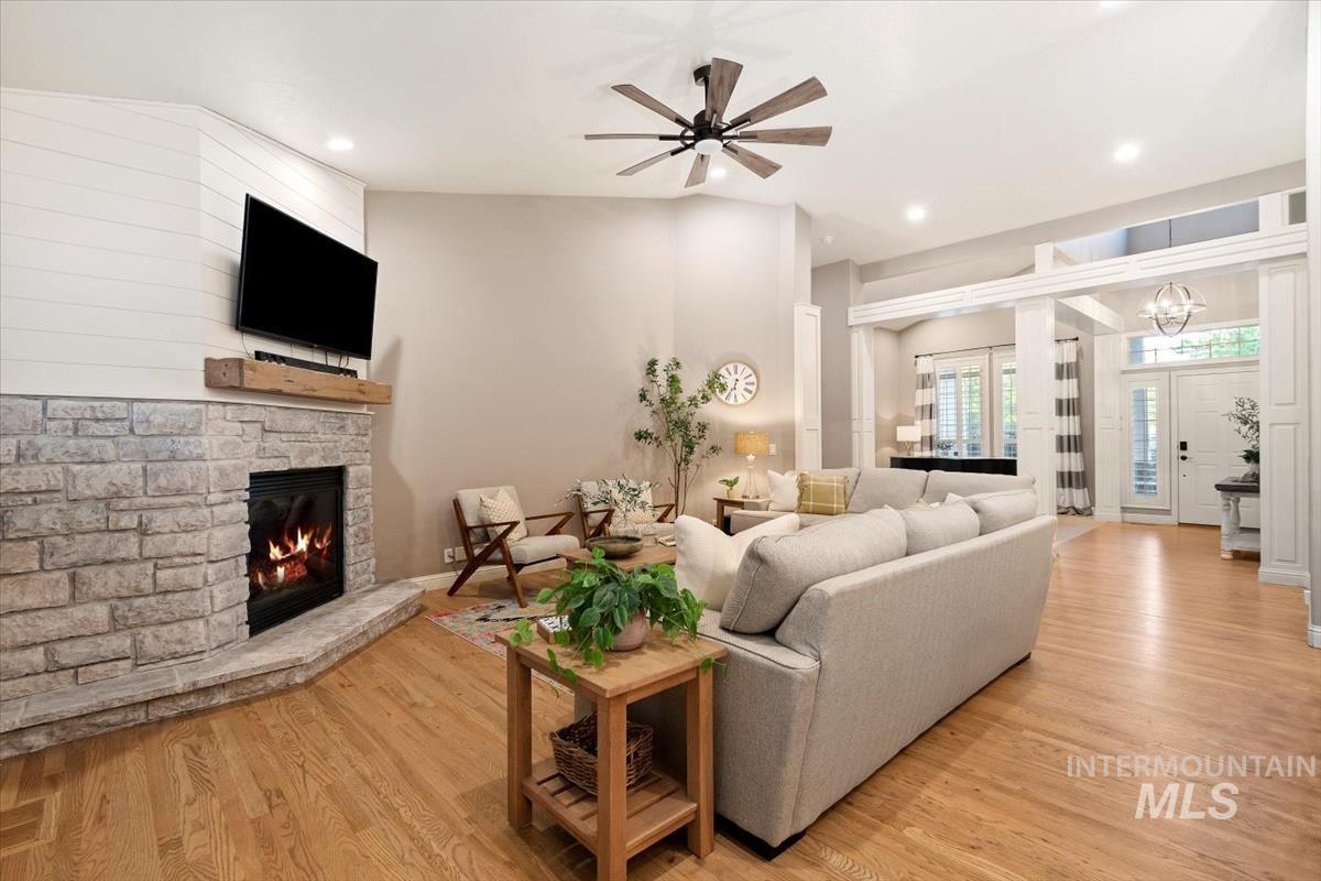 Living area featuring light wood-type flooring, a ceiling fan, recessed lighting, and a stone fireplace