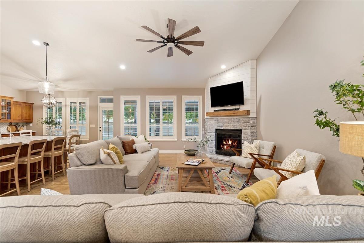 Living room with lofted ceiling, recessed lighting, a fireplace, a chandelier, and ceiling fan