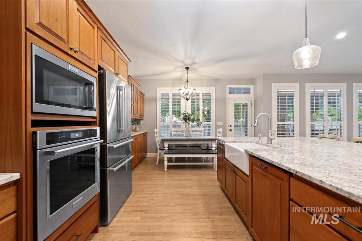 Kitchen featuring brown cabinets, hanging light fixtures, and stainless steel appliances