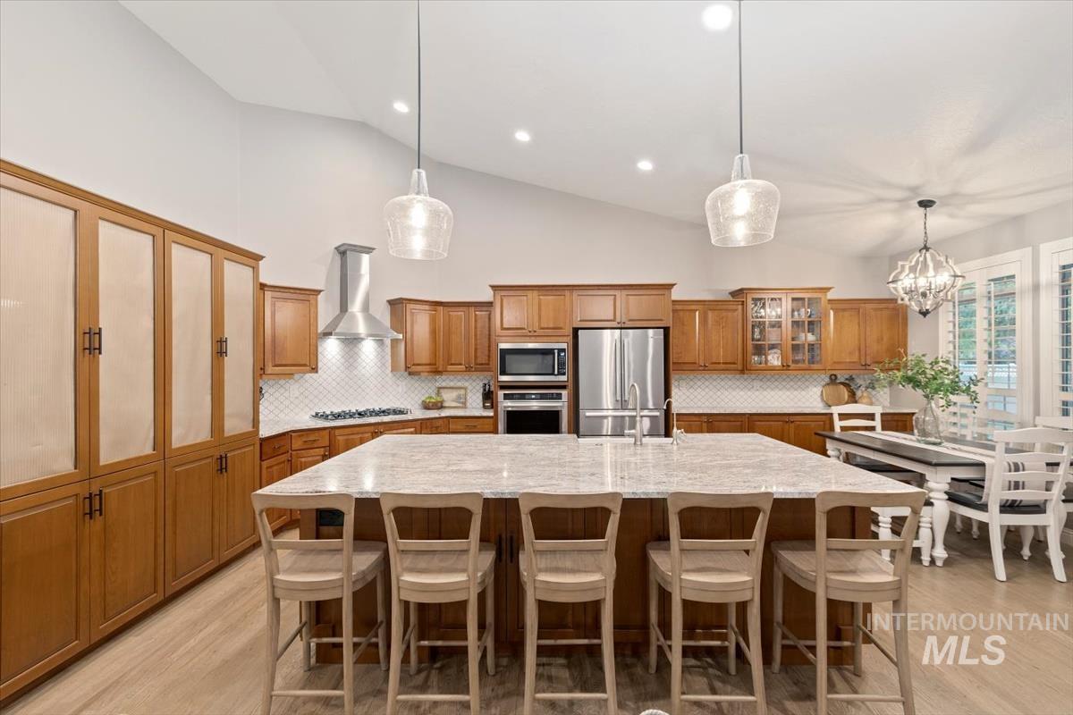 Kitchen featuring brown cabinetry, tasteful backsplash, a breakfast bar, high vaulted ceiling, and recessed lighting