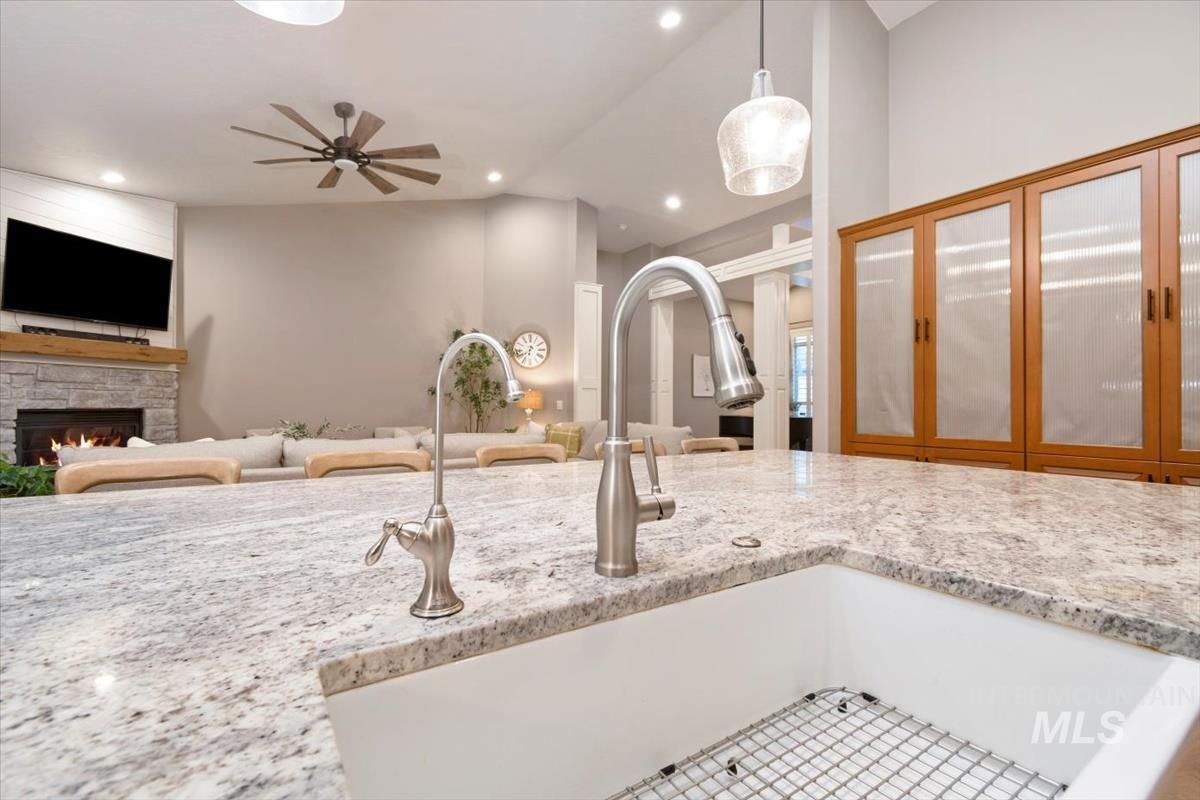 Kitchen featuring decorative light fixtures, open floor plan, light stone countertops, a stone fireplace, and recessed lighting