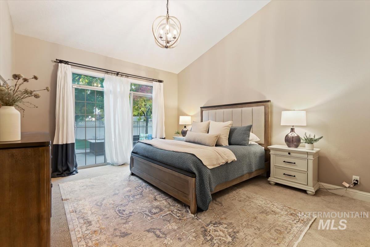 Bedroom featuring vaulted ceiling, access to outside, carpet floors, and a chandelier