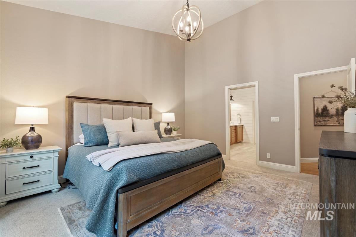 Bedroom featuring light carpet, a chandelier, a high ceiling, and ensuite bathroom