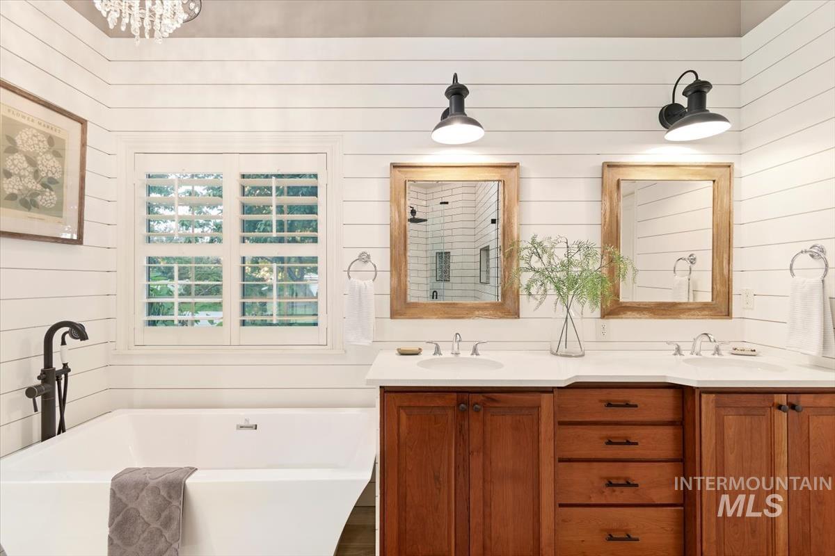 Full bath with wooden walls, double vanity, a freestanding bath, and a shower stall