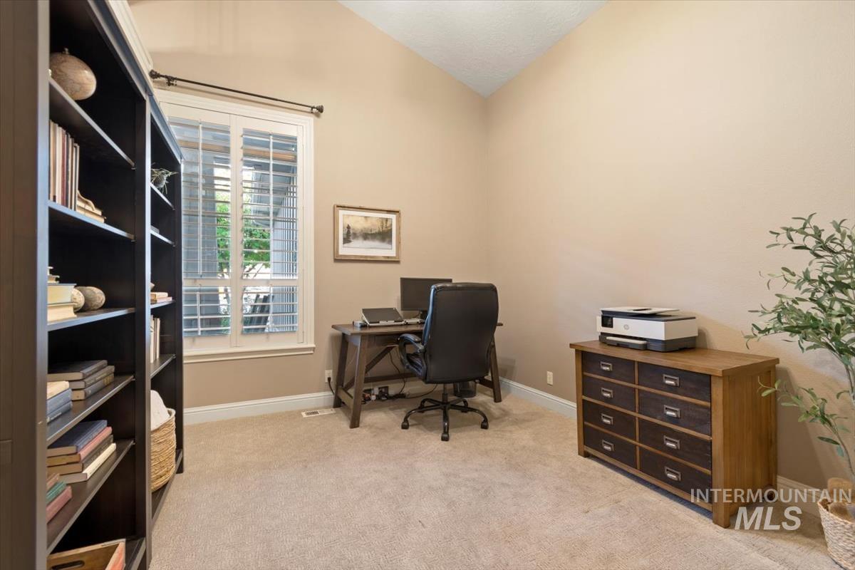 Office space featuring light colored carpet and vaulted ceiling