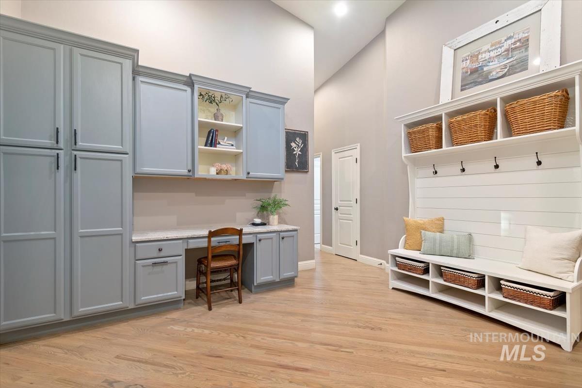 Mudroom with built in study area, a towering ceiling, and light wood-style floors
