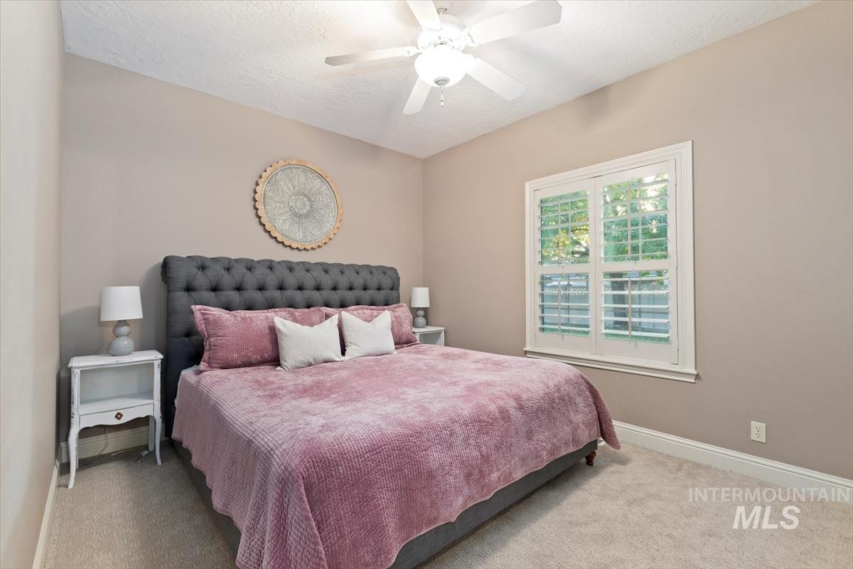 Bedroom with carpet flooring, a textured ceiling, and ceiling fan