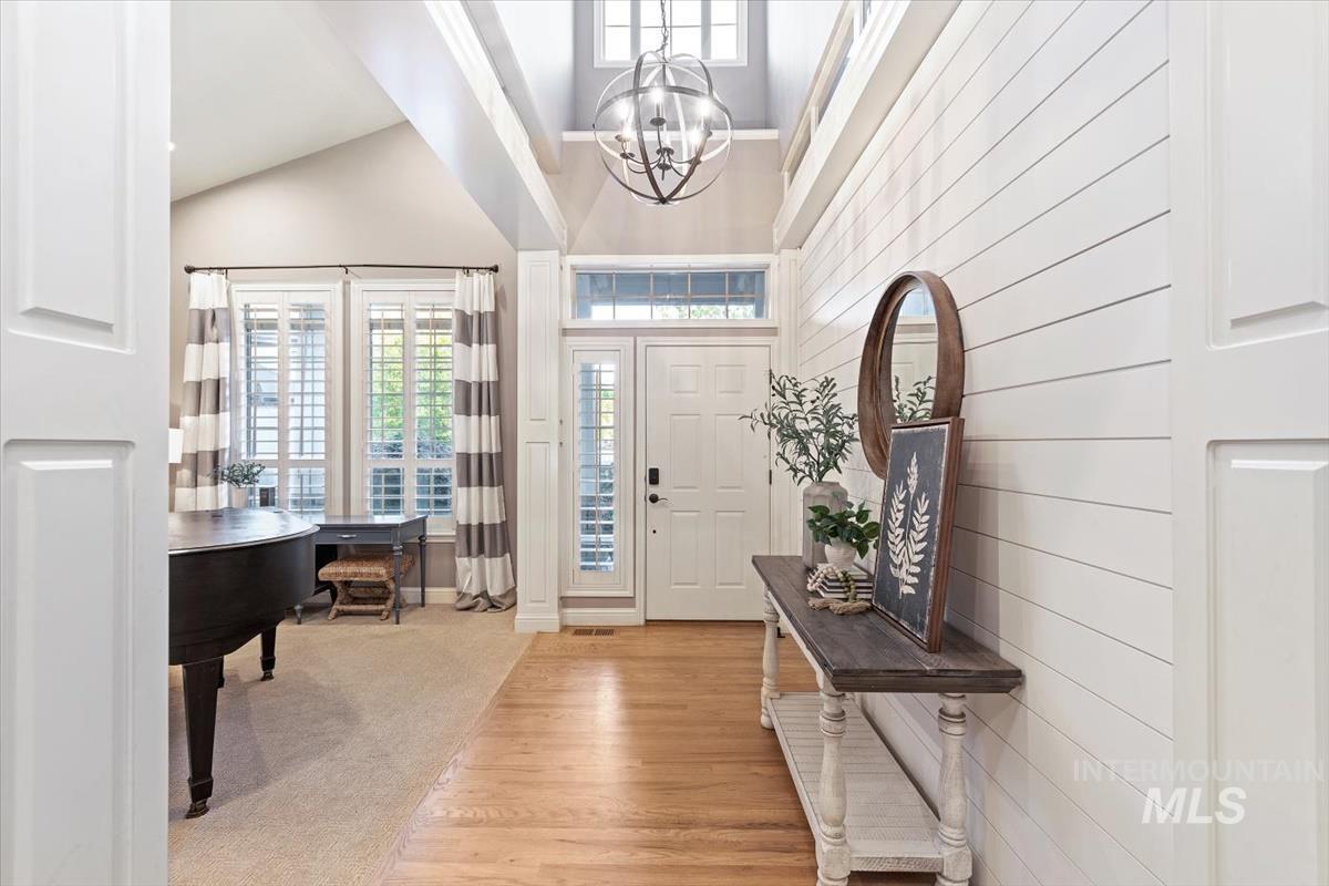Entrance foyer with light wood-style floors, a towering ceiling, and a chandelier