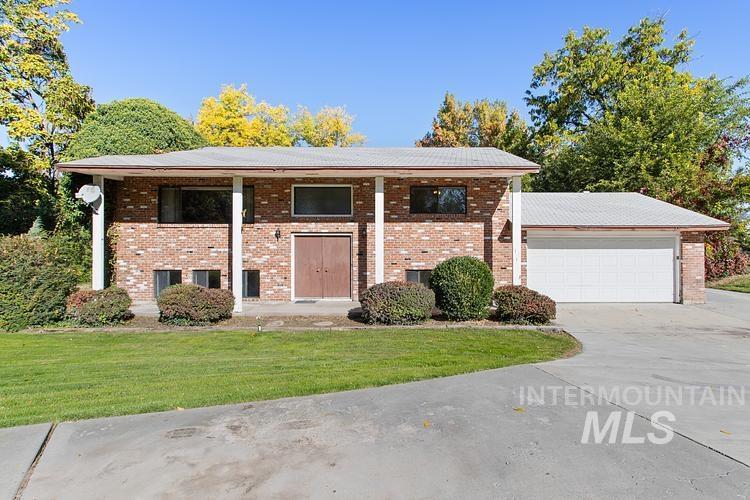 Split foyer home with brick siding, a front lawn, a garage, a porch, and driveway