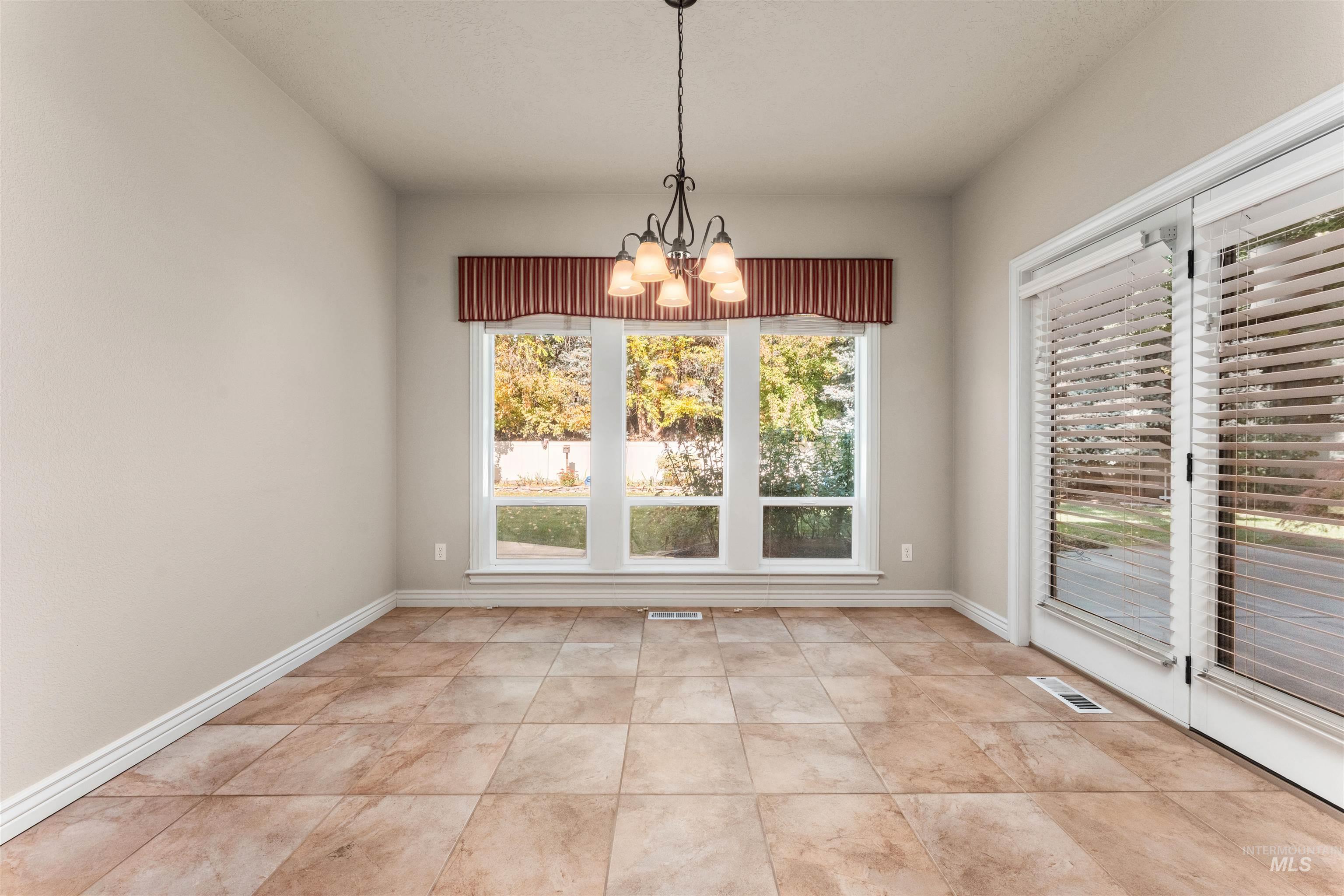 Unfurnished dining area with a chandelier and baseboards