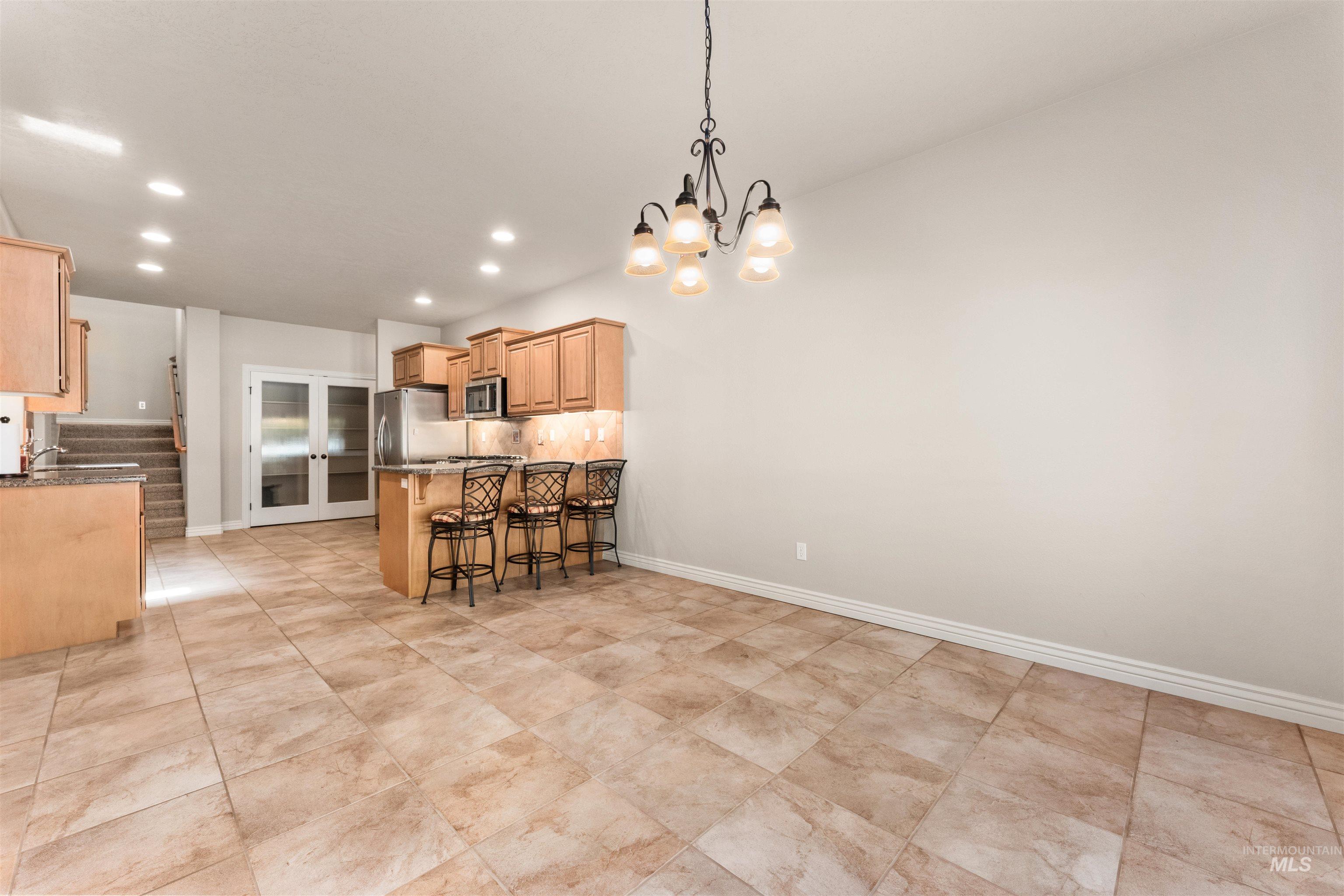 Kitchen featuring tasteful backsplash, a kitchen breakfast bar, a peninsula, decorative light fixtures, and recessed lighting