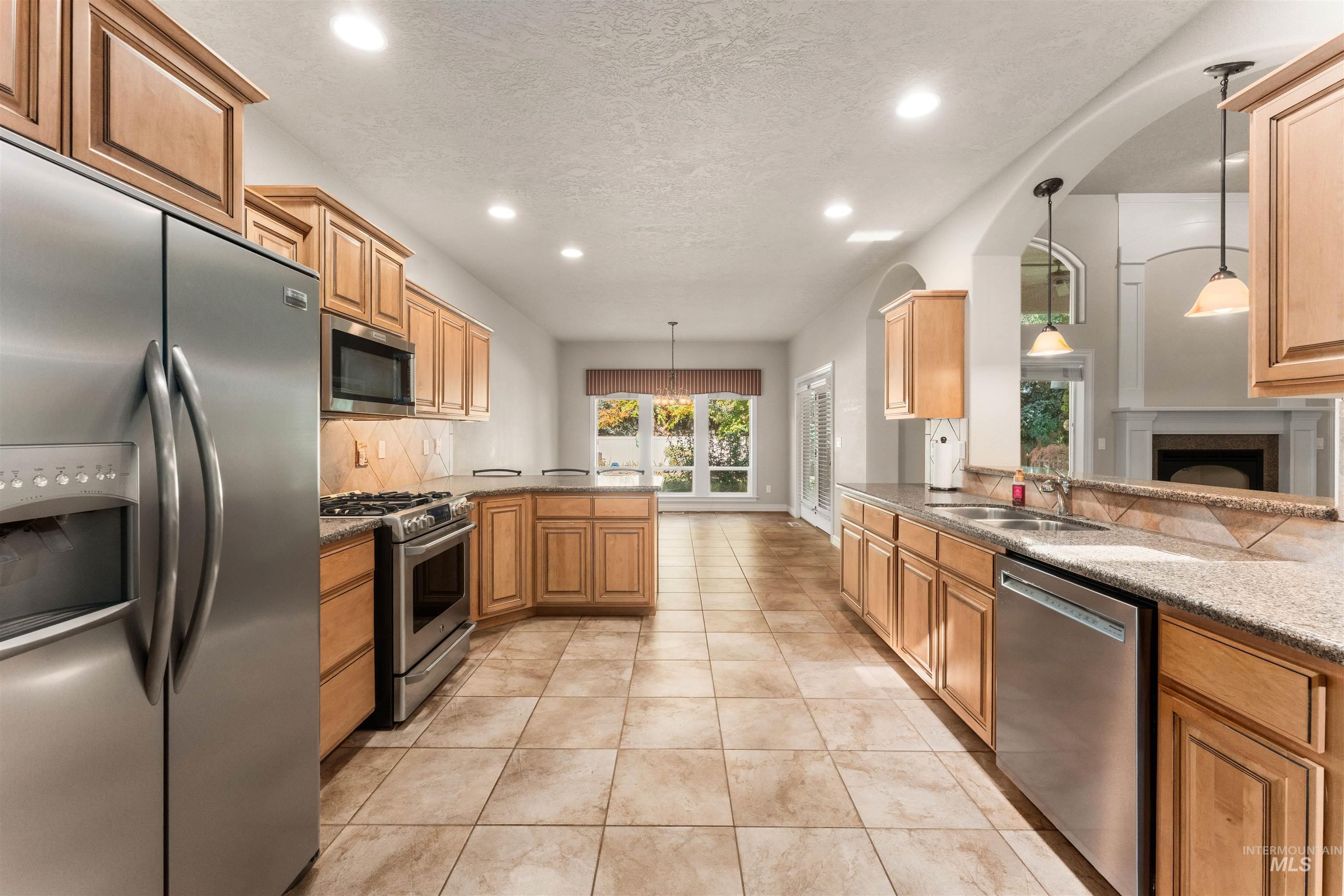Kitchen featuring a peninsula, stainless steel appliances, hanging light fixtures, recessed lighting, and light tile patterned floors