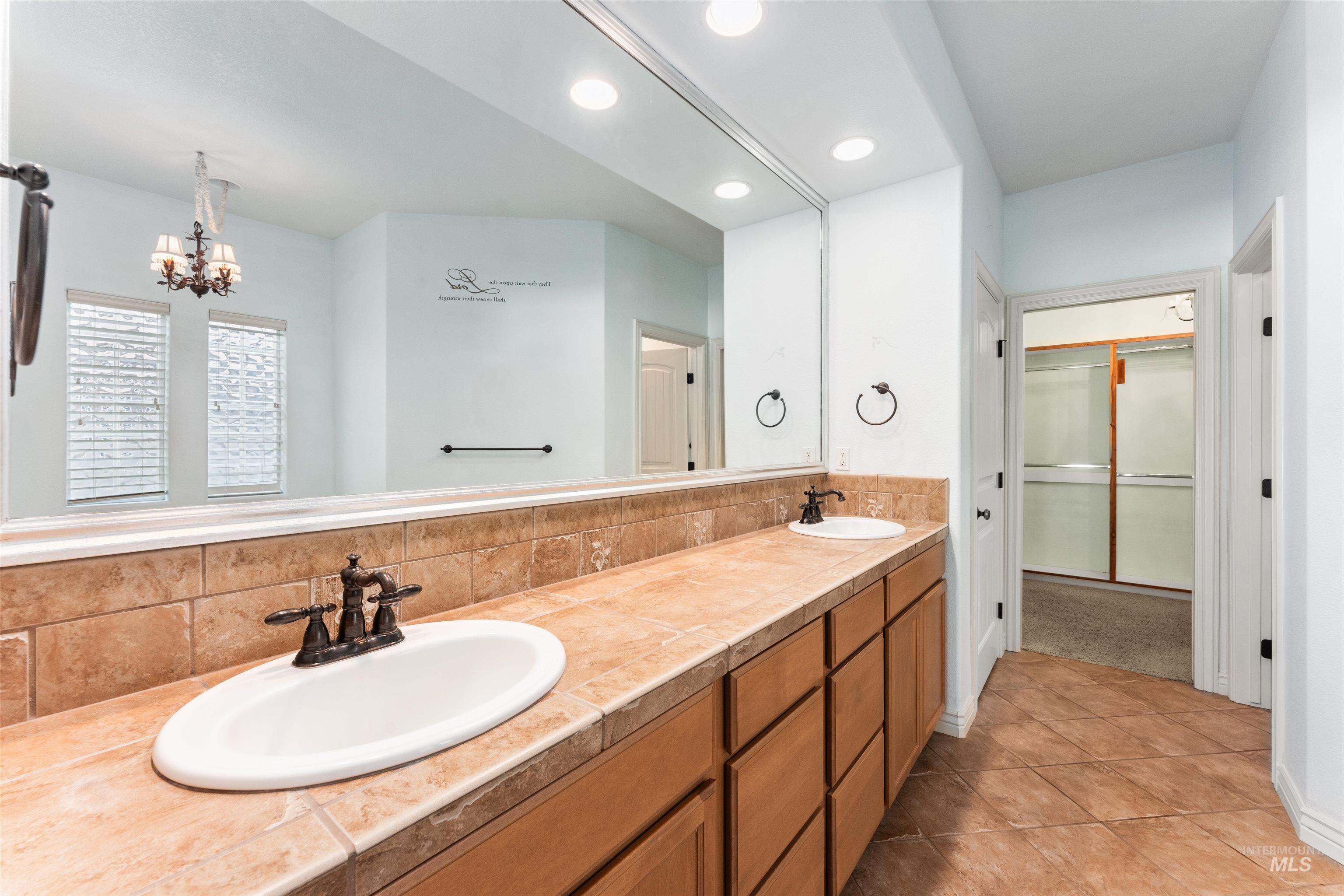 Full bathroom with double vanity, recessed lighting, light tile patterned floors, a walk in closet, and a chandelier