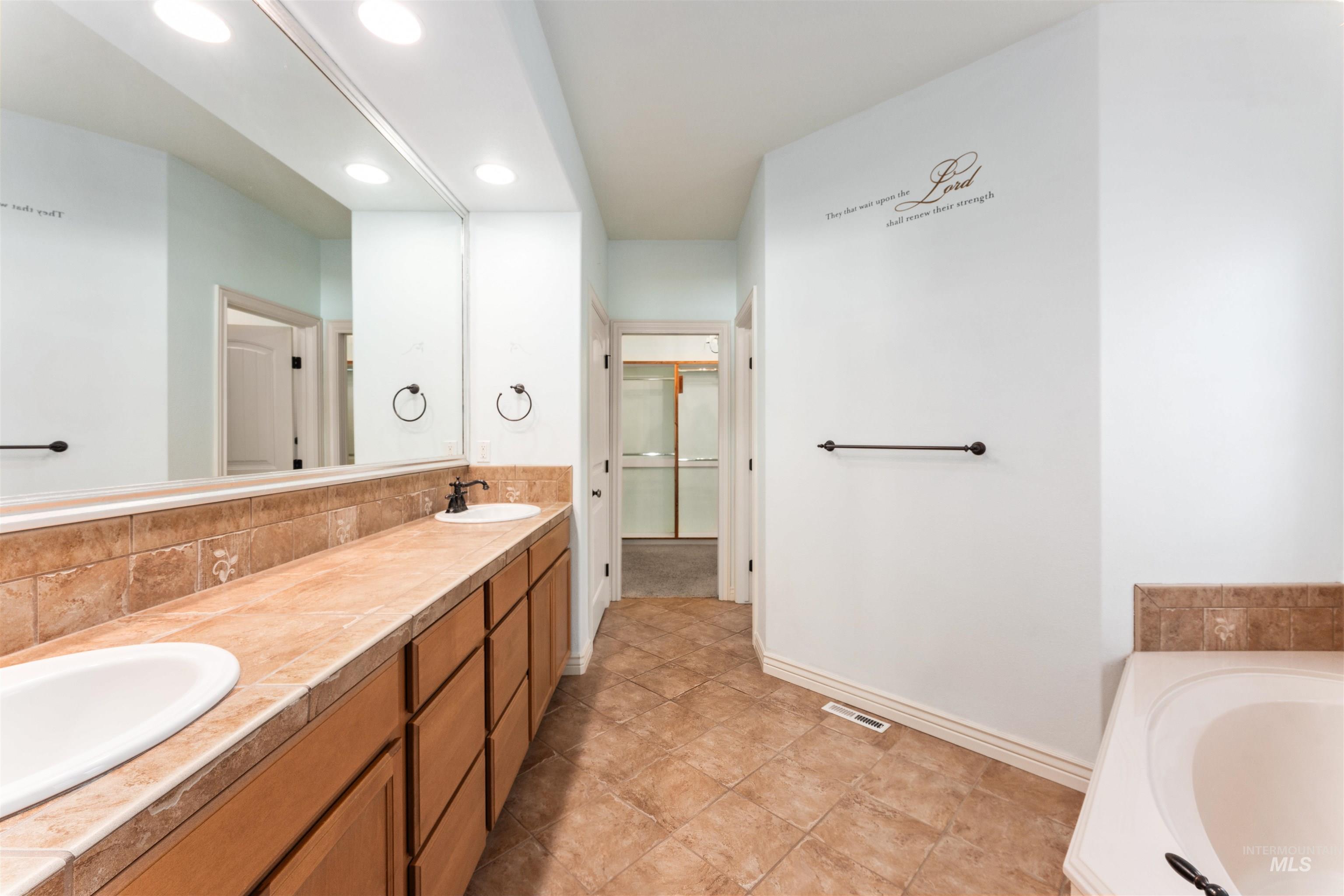 Bathroom with a garden tub, double vanity, and recessed lighting