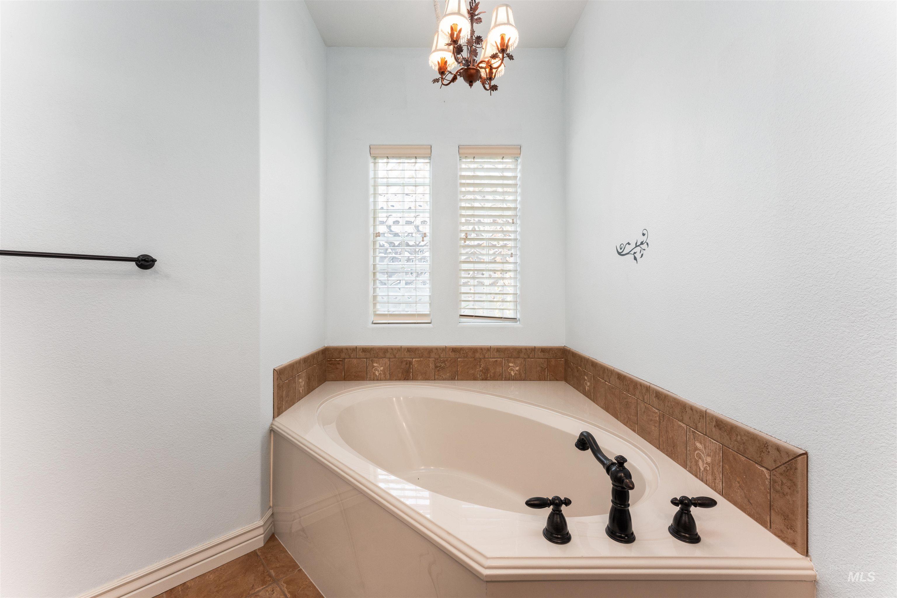 Bathroom featuring a bath, a chandelier, and tile patterned flooring