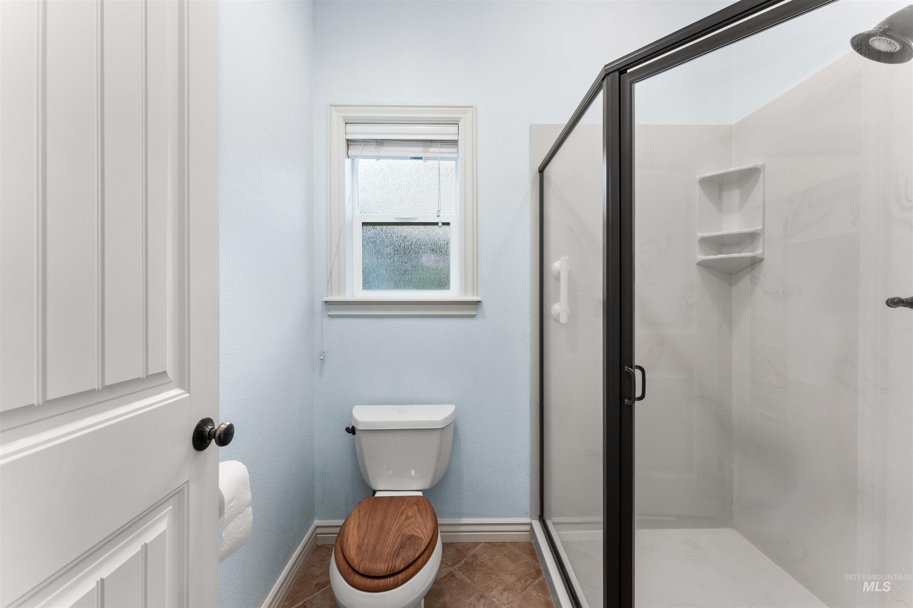 Full bathroom featuring a shower stall and tile patterned floors
