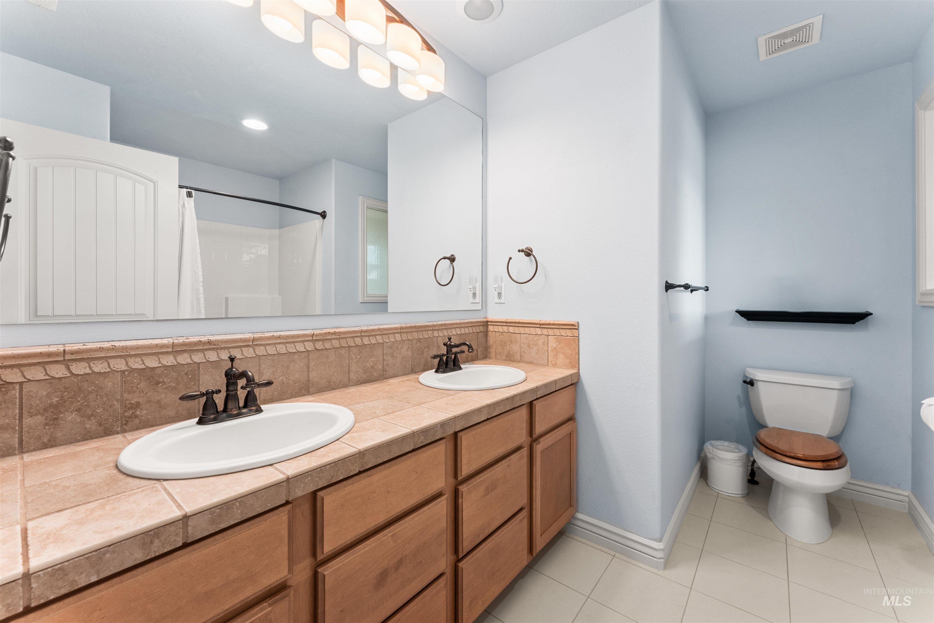 Bathroom with light tile patterned flooring, double vanity, and a shower with curtain