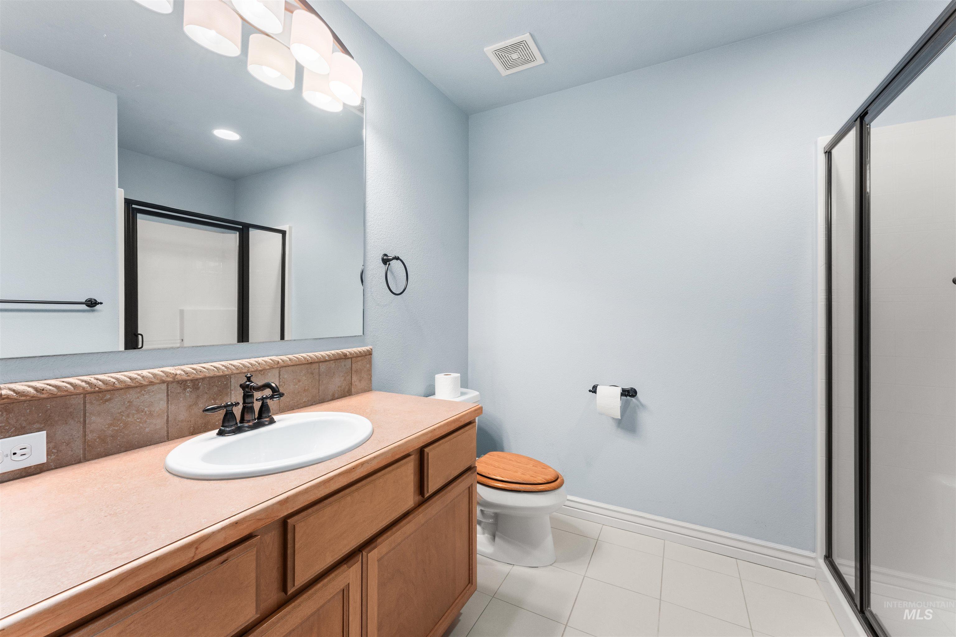 Full bath with a stall shower, vanity, and light tile patterned flooring