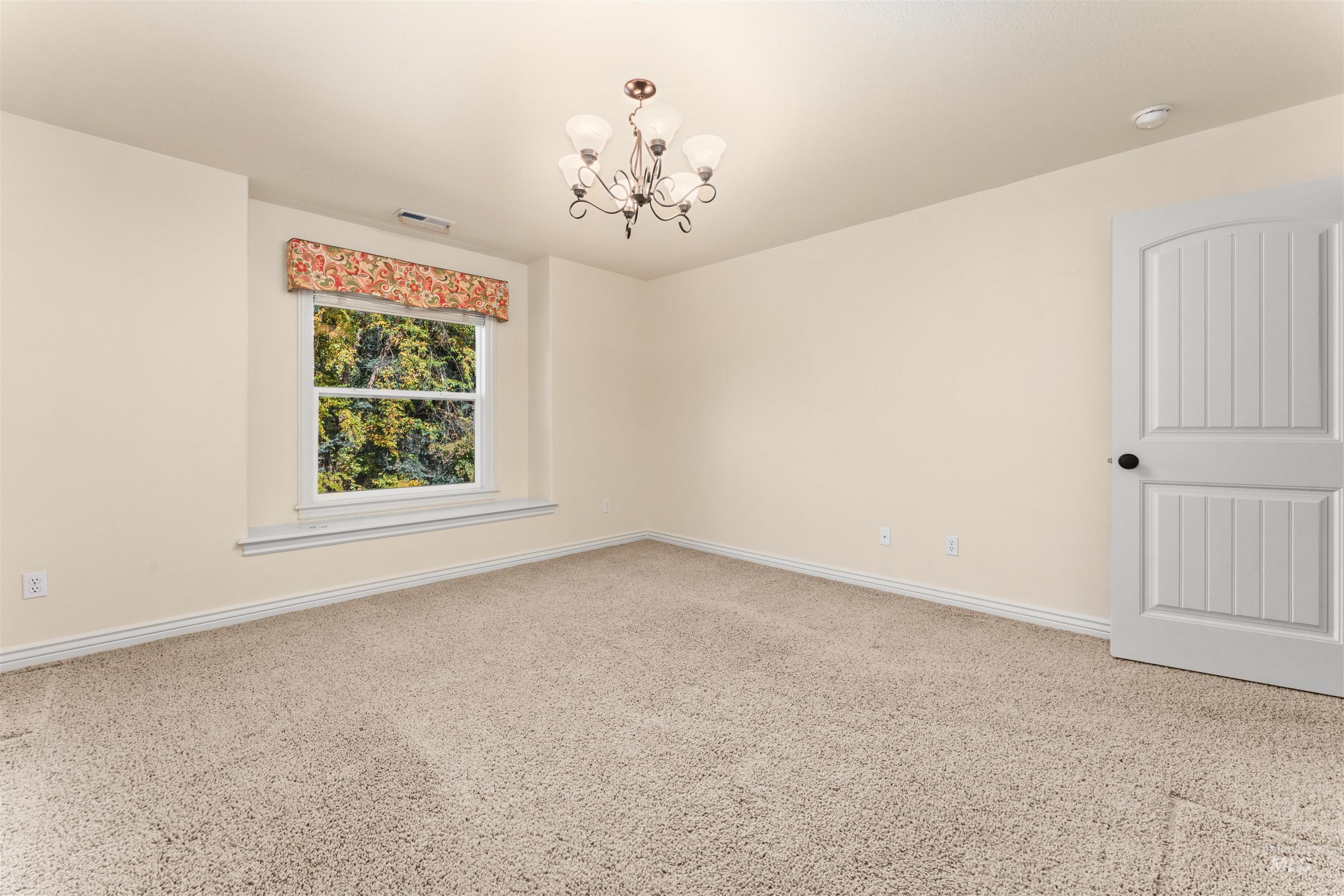 Spare room with a chandelier and carpet