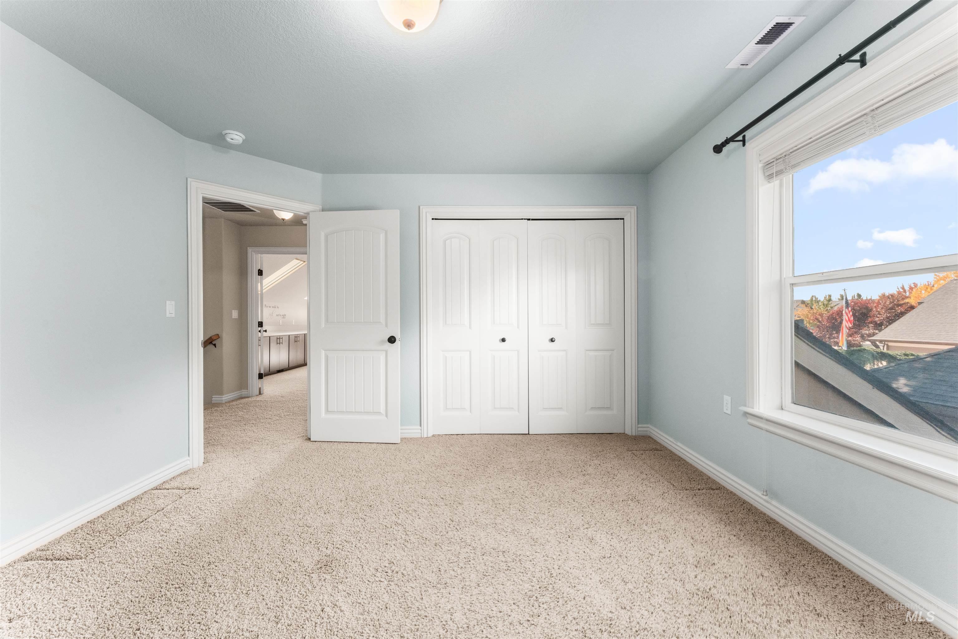 Unfurnished bedroom featuring light carpet and a closet