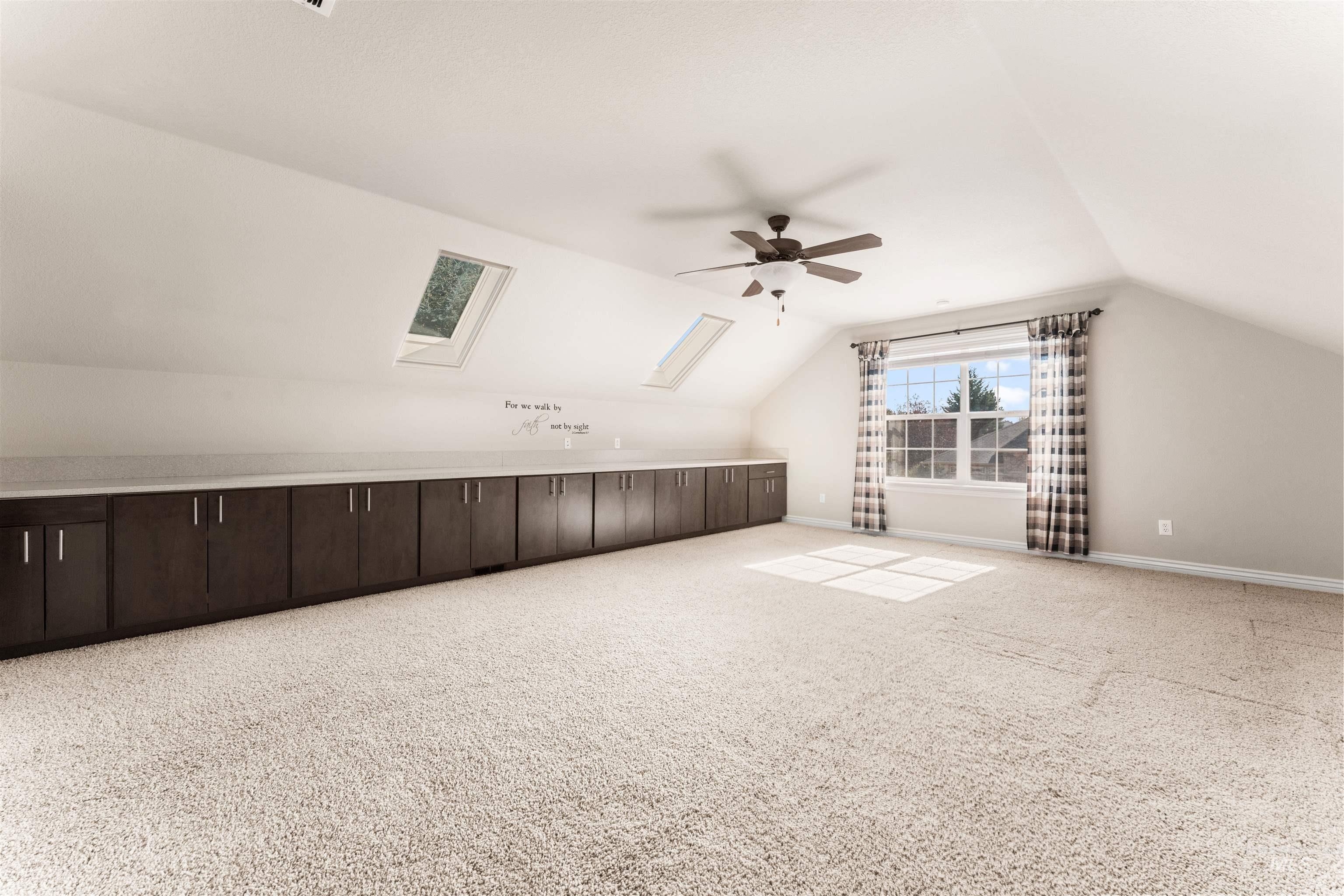 Bonus room with lofted ceiling, a skylight, light carpet, and ceiling fan