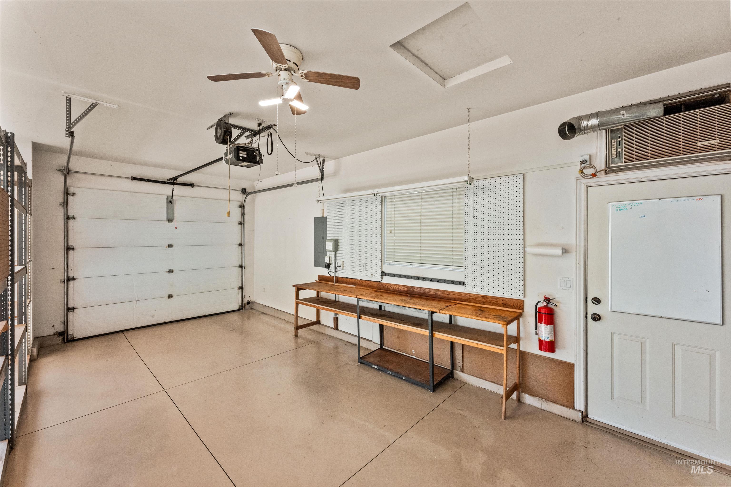 Garage with a ceiling fan, electric panel, and a garage door opener