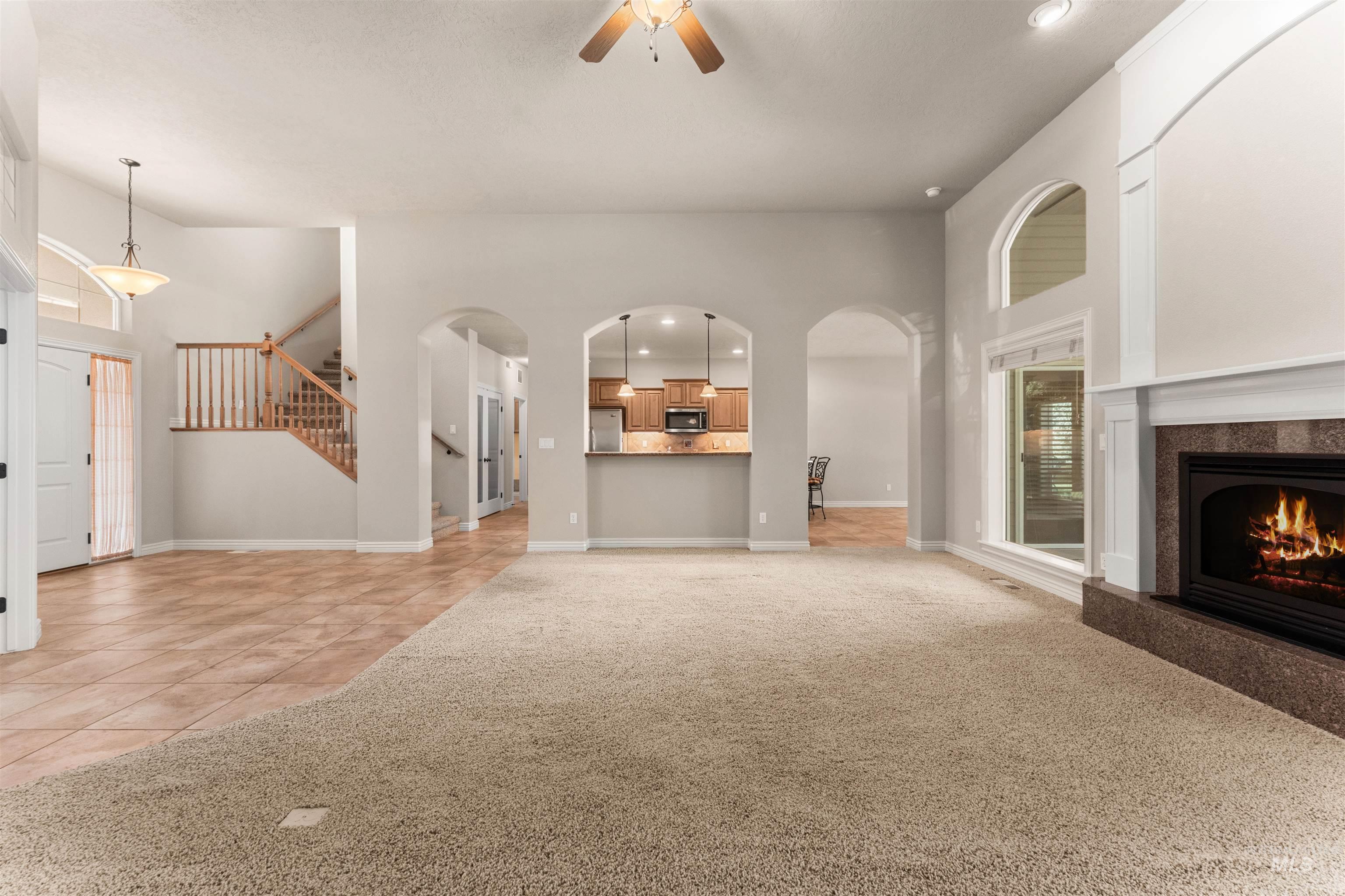 Unfurnished living room featuring recessed lighting, light carpet, light tile patterned floors, ceiling fan, and stairway