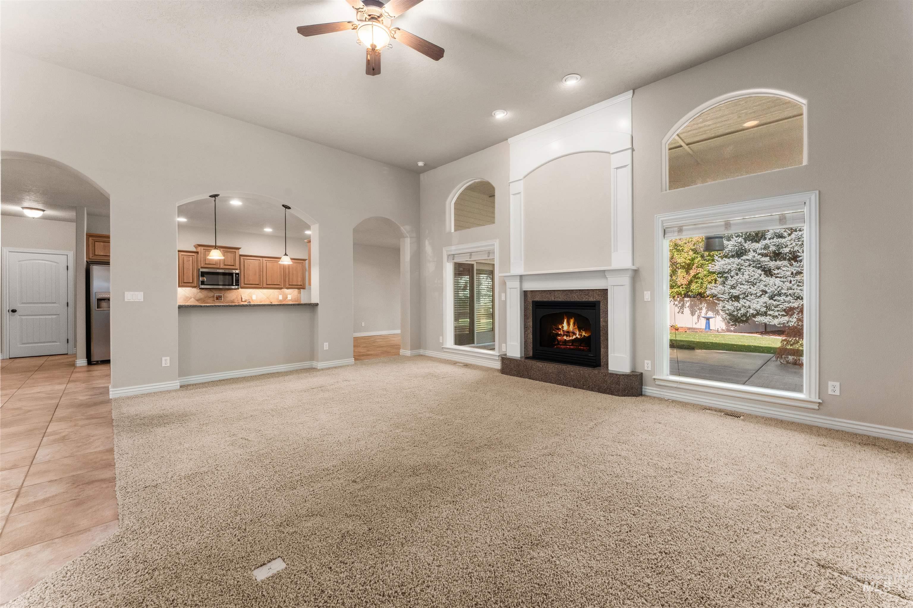 Unfurnished living room featuring recessed lighting, light carpet, arched walkways, light tile patterned floors, and a tiled fireplace