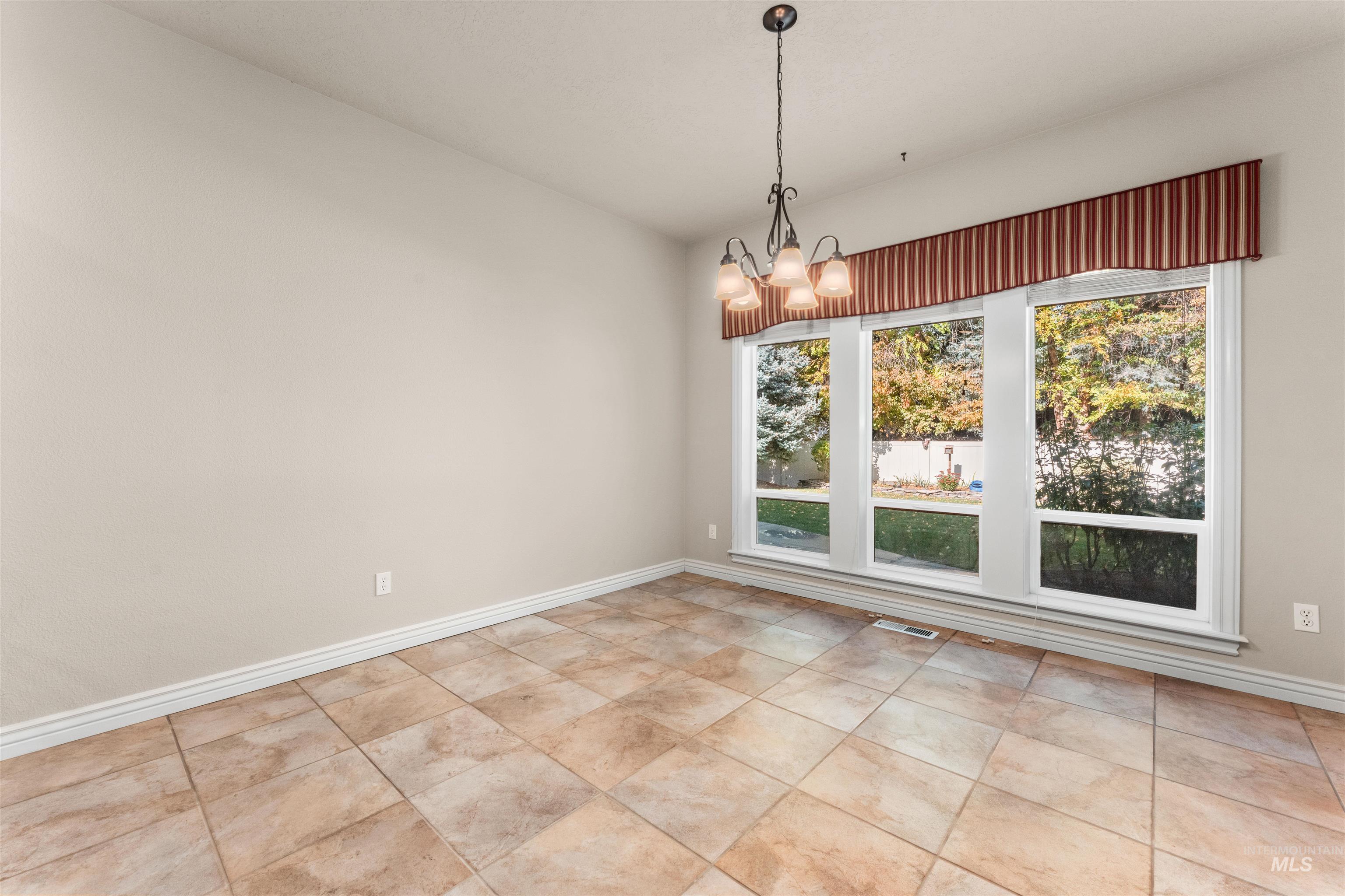Unfurnished dining area with a chandelier and baseboards