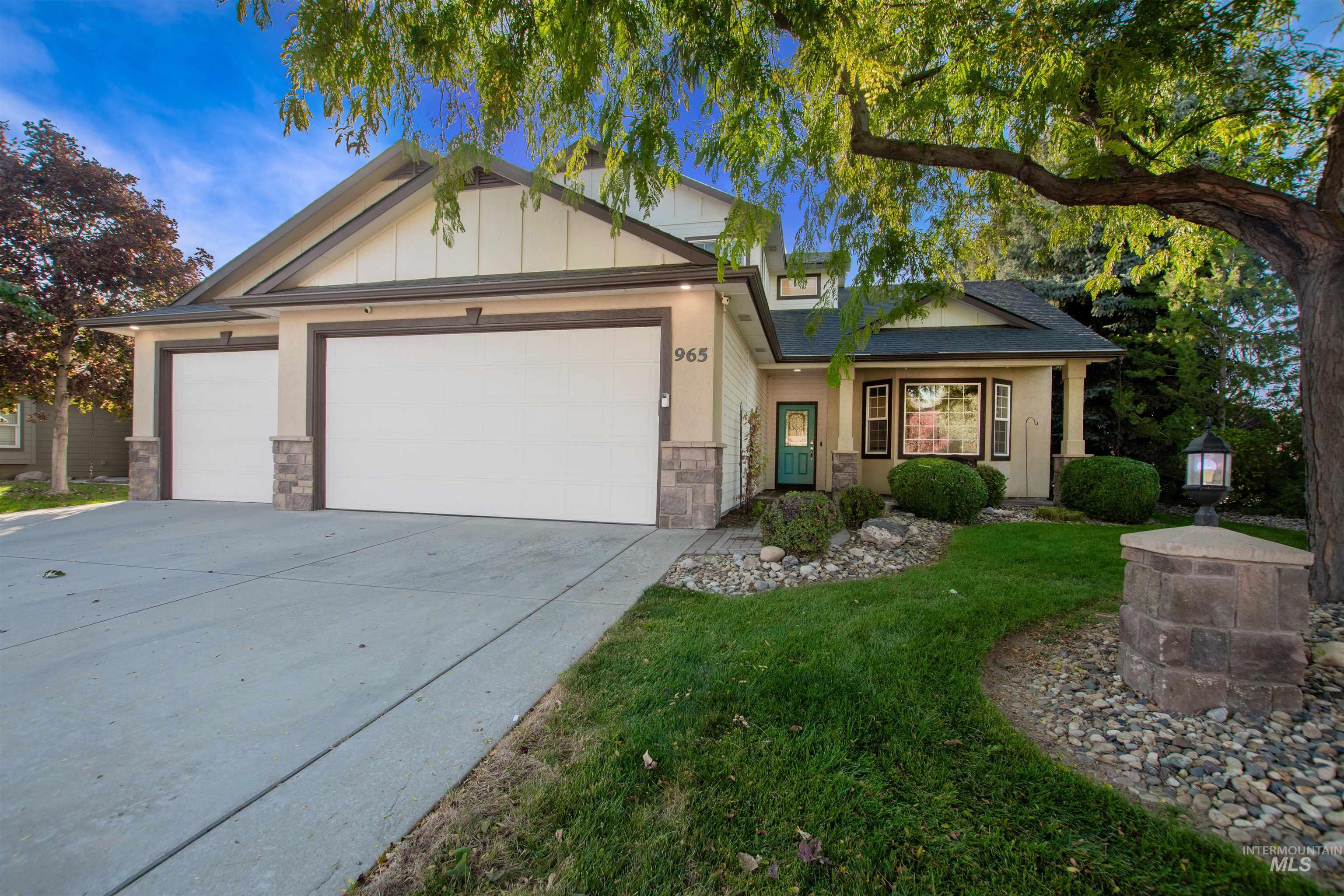 View of front of house featuring stone siding, a garage, driveway, a front lawn, and board and batten siding