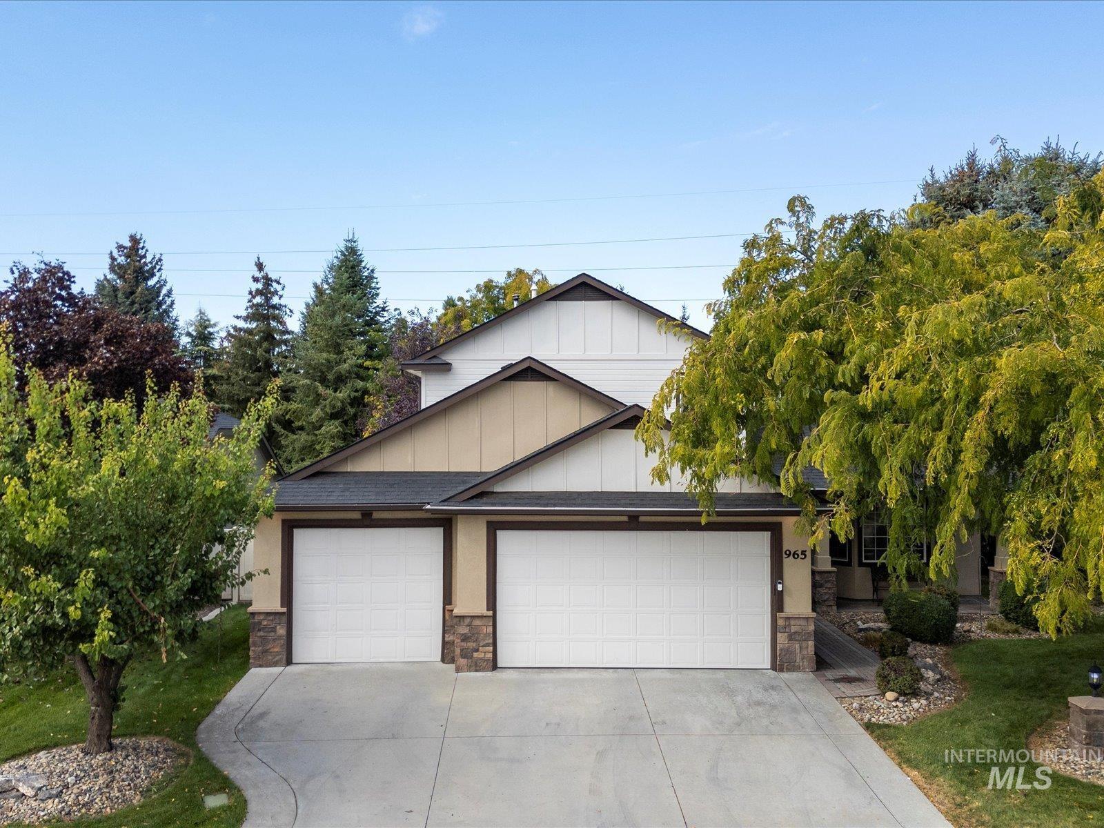 View of front of home with board and batten siding, stone siding, an attached garage, and driveway