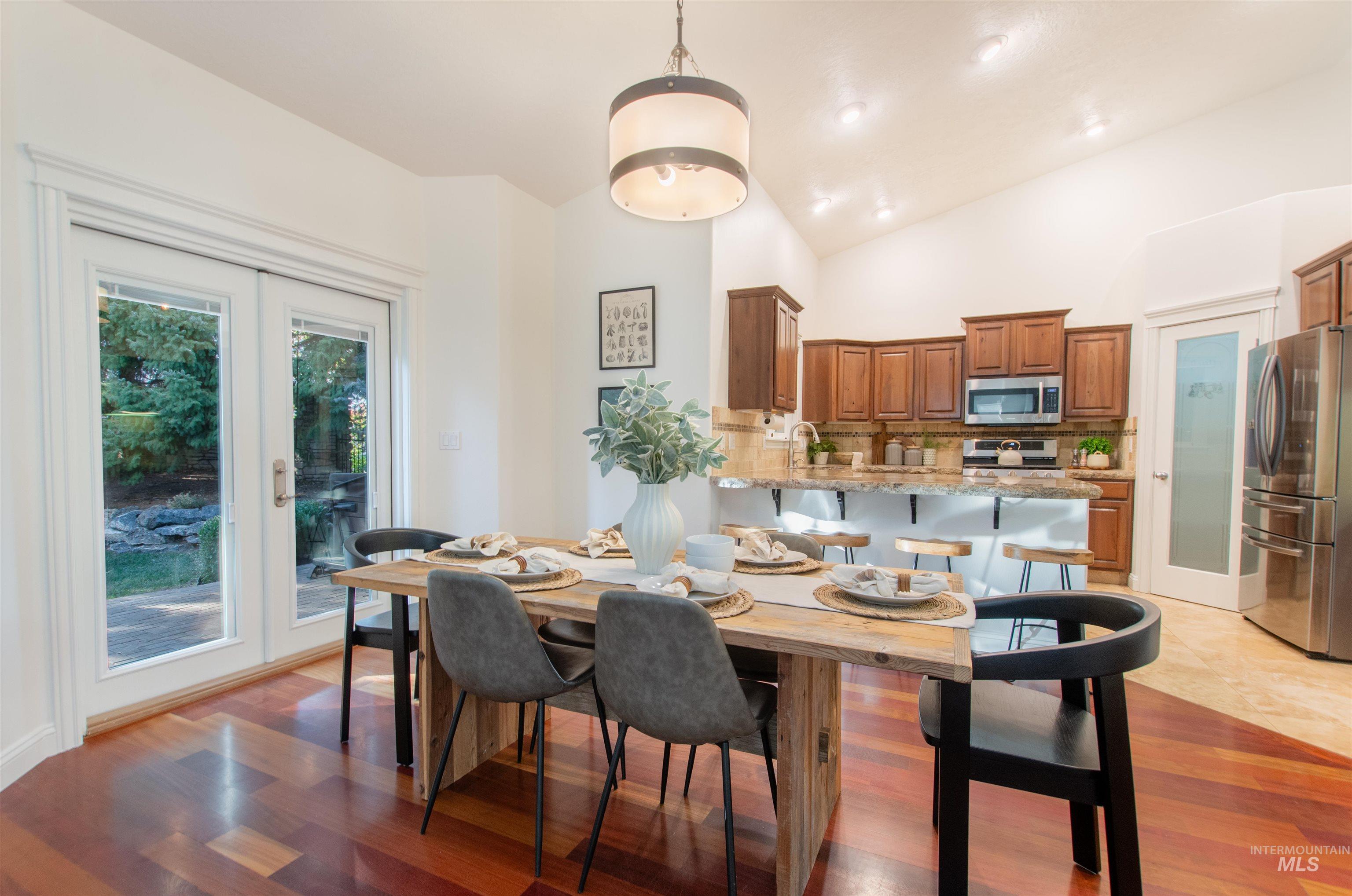 Dining room with light wood-type flooring, high vaulted ceiling, and french doors