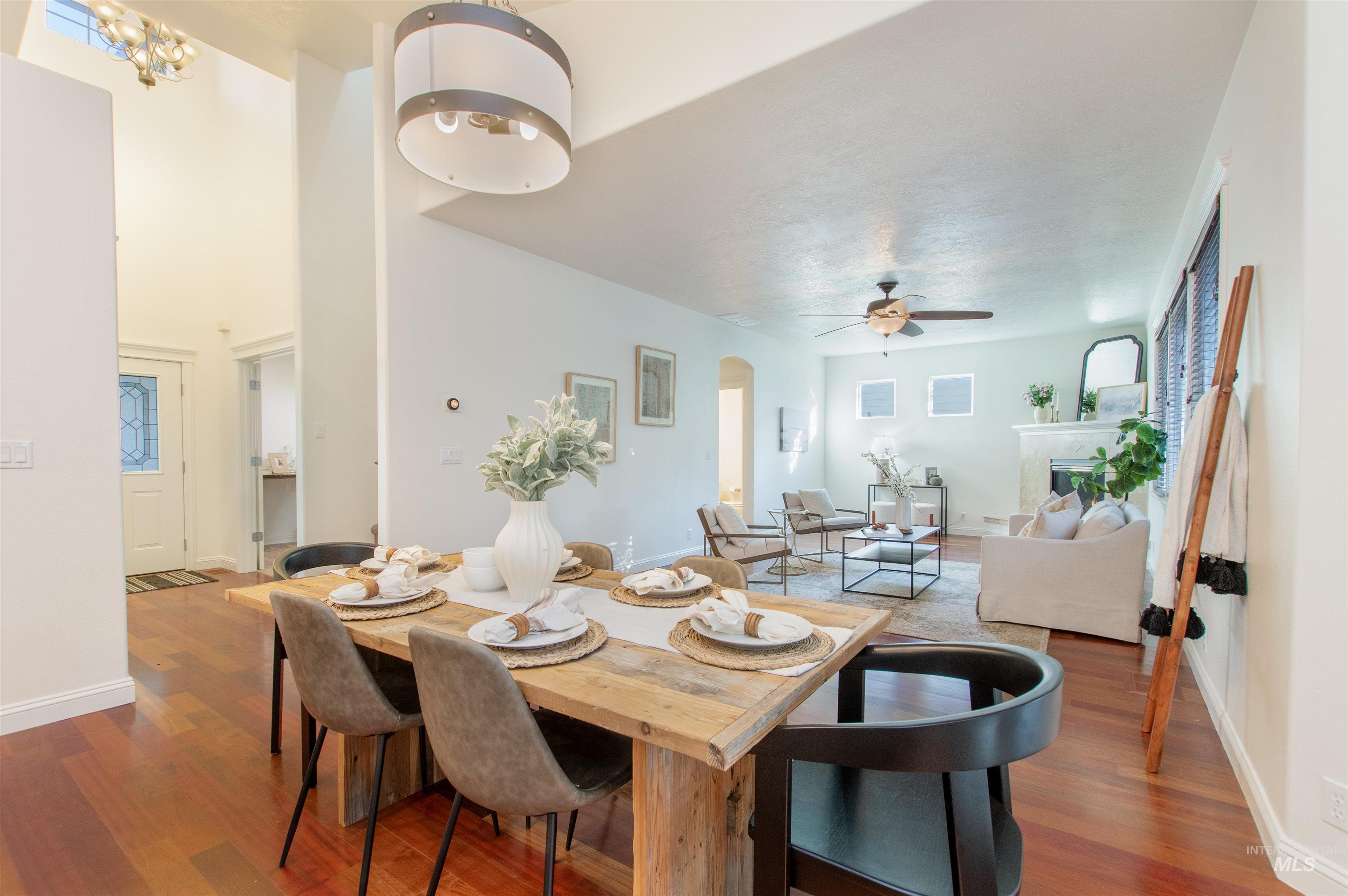 Dining space featuring arched walkways, dark wood-type flooring, a fireplace, and ceiling fan