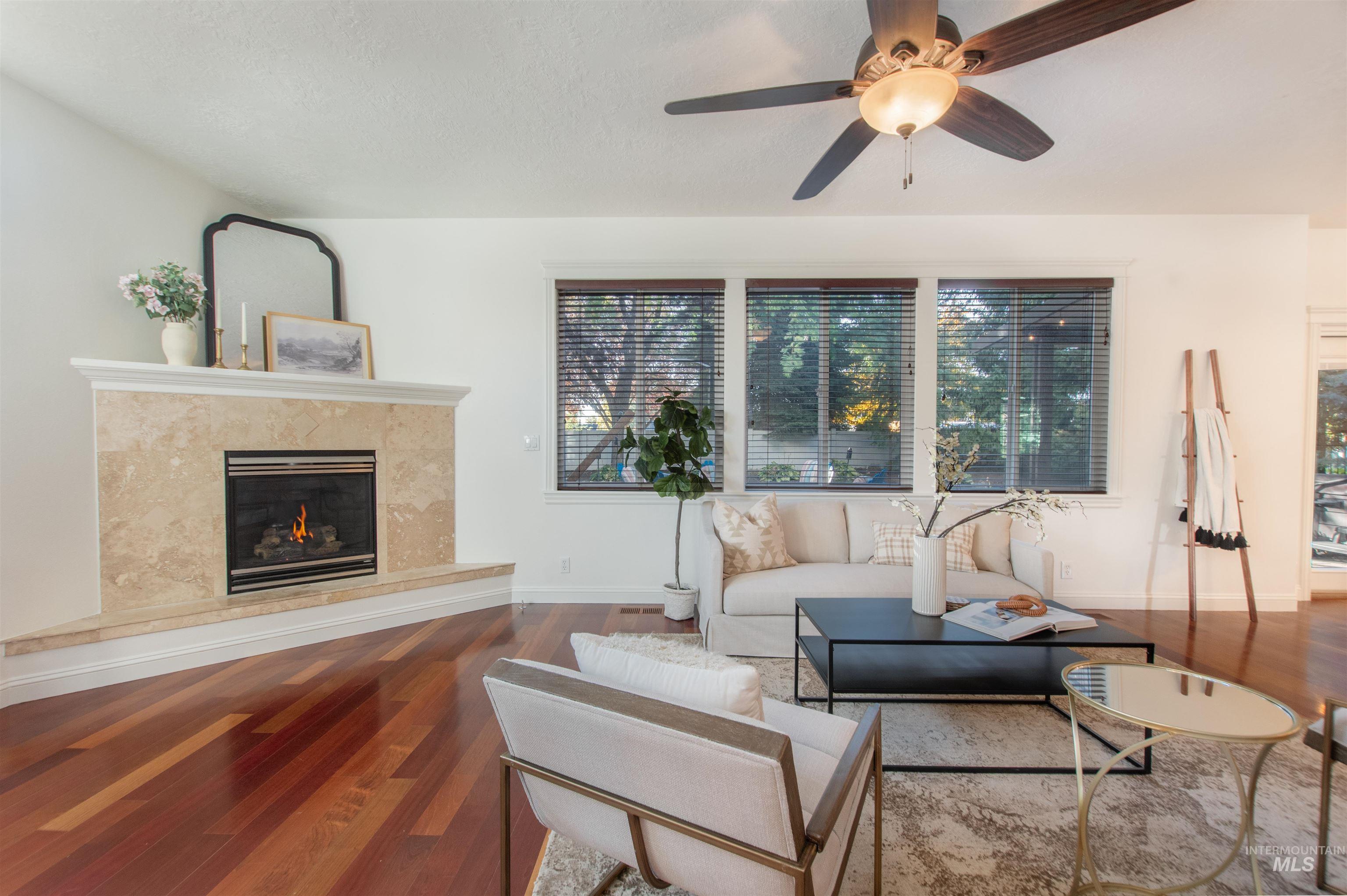 Living room with wood finished floors, a high end fireplace, and ceiling fan