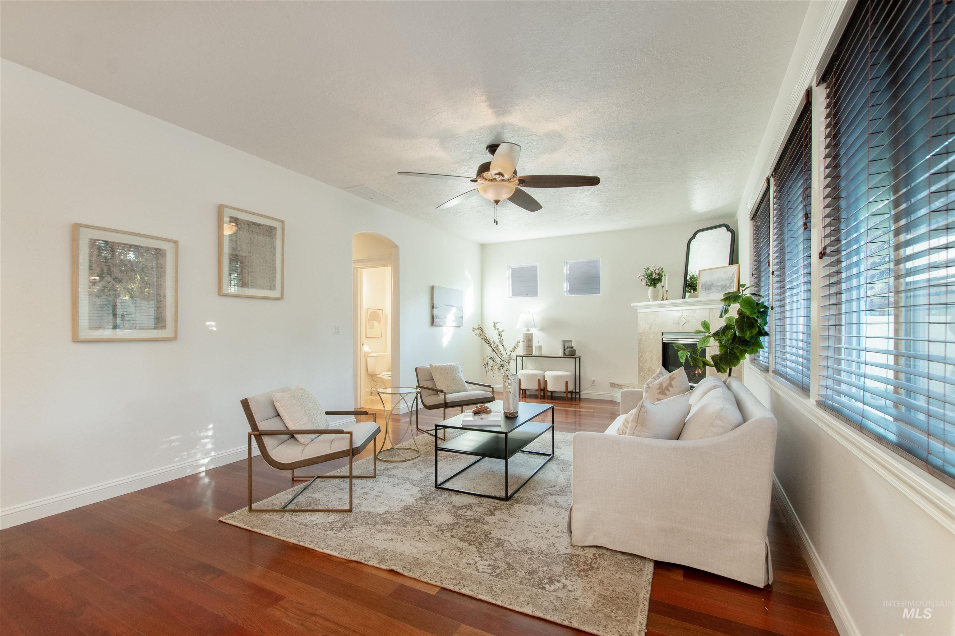 Living area featuring arched walkways, dark wood finished floors, and a ceiling fan