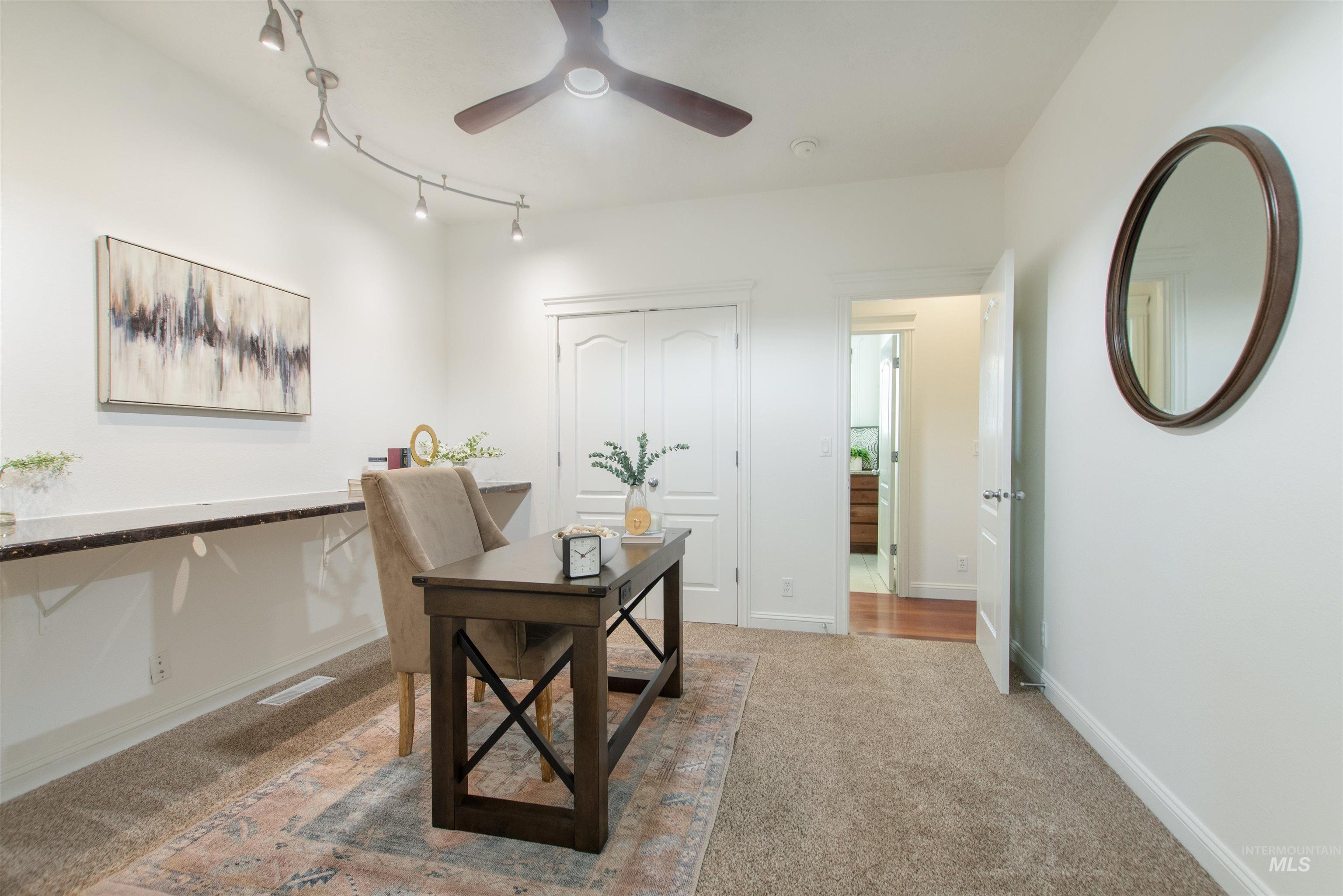 Office featuring light colored carpet, track lighting, and a ceiling fan