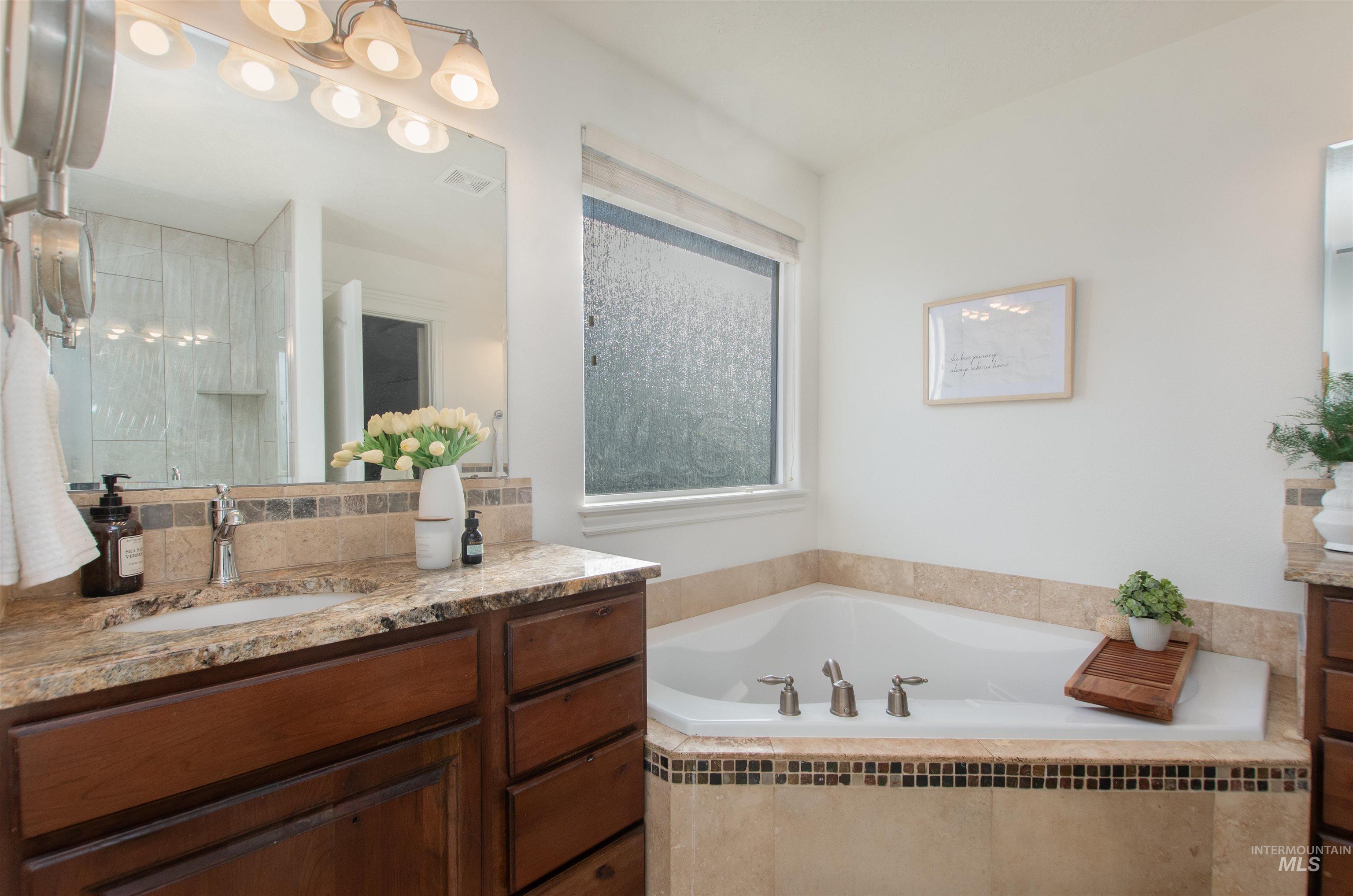 Full bath featuring vanity, a garden tub, and a shower stall