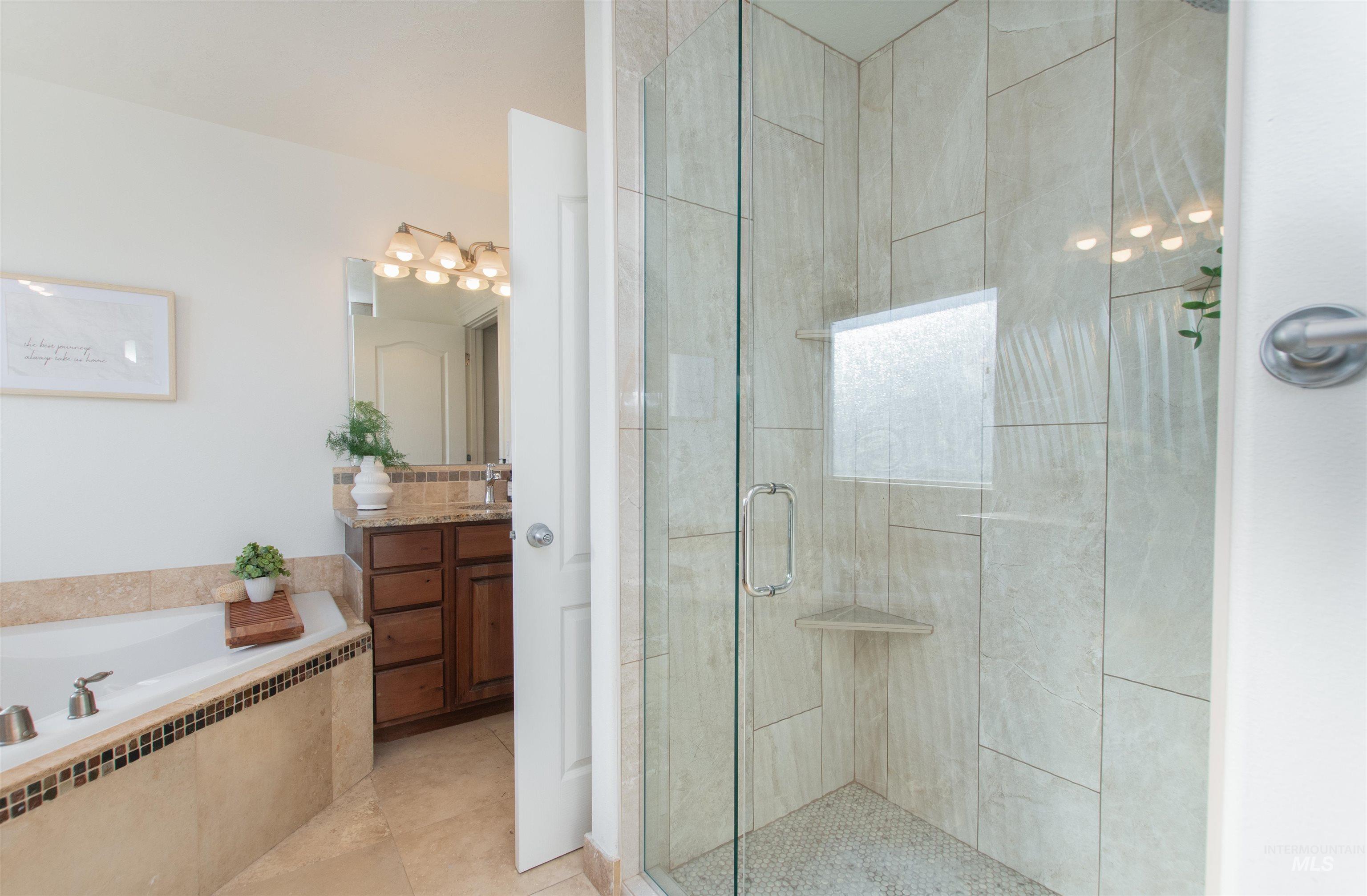 Bathroom featuring vanity, a stall shower, a garden tub, radiator, and light tile patterned flooring