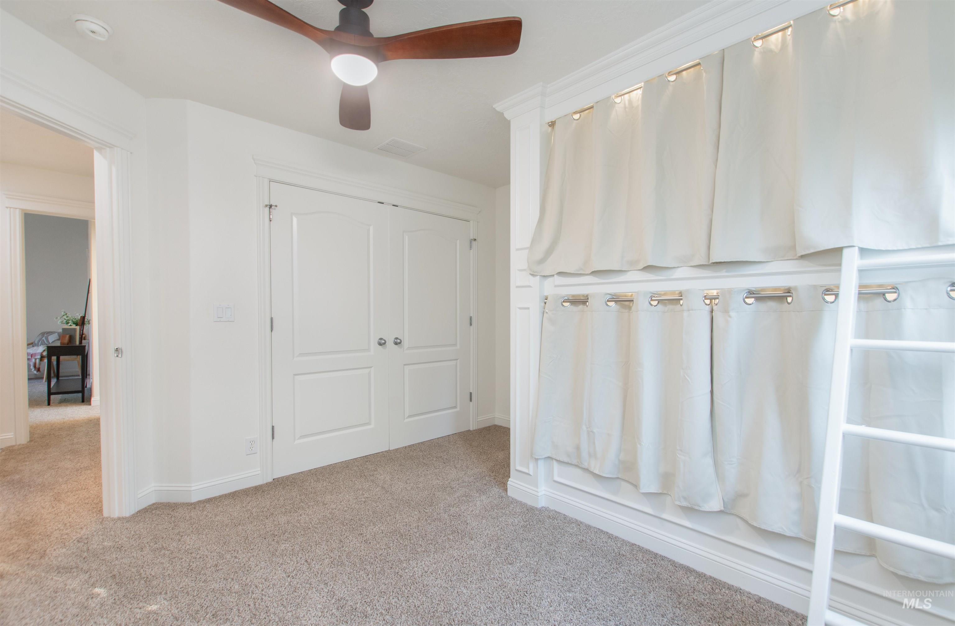 Unfurnished bedroom with light carpet, a closet, and a ceiling fan