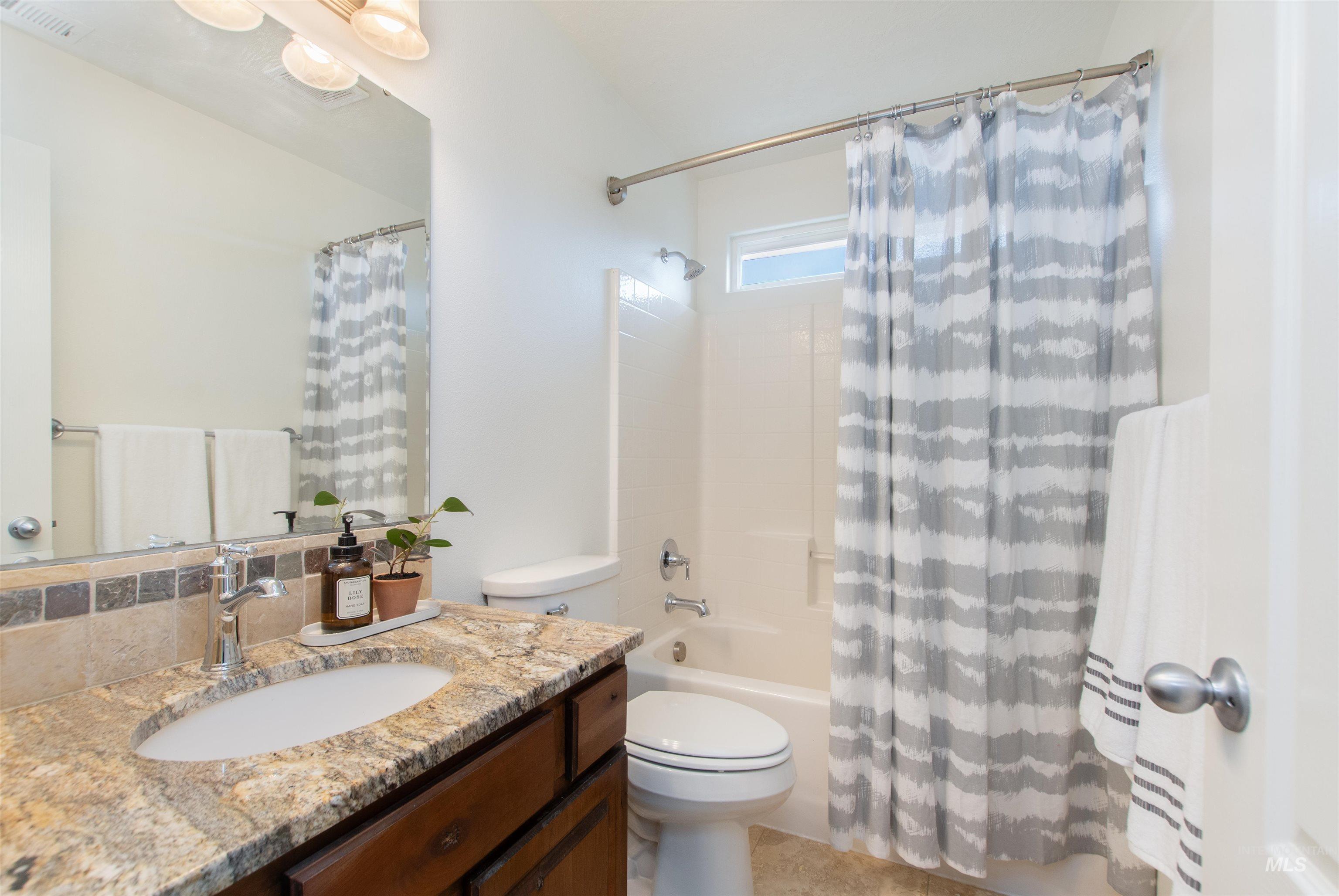 Full bathroom featuring shower / bath combination with curtain and vanity