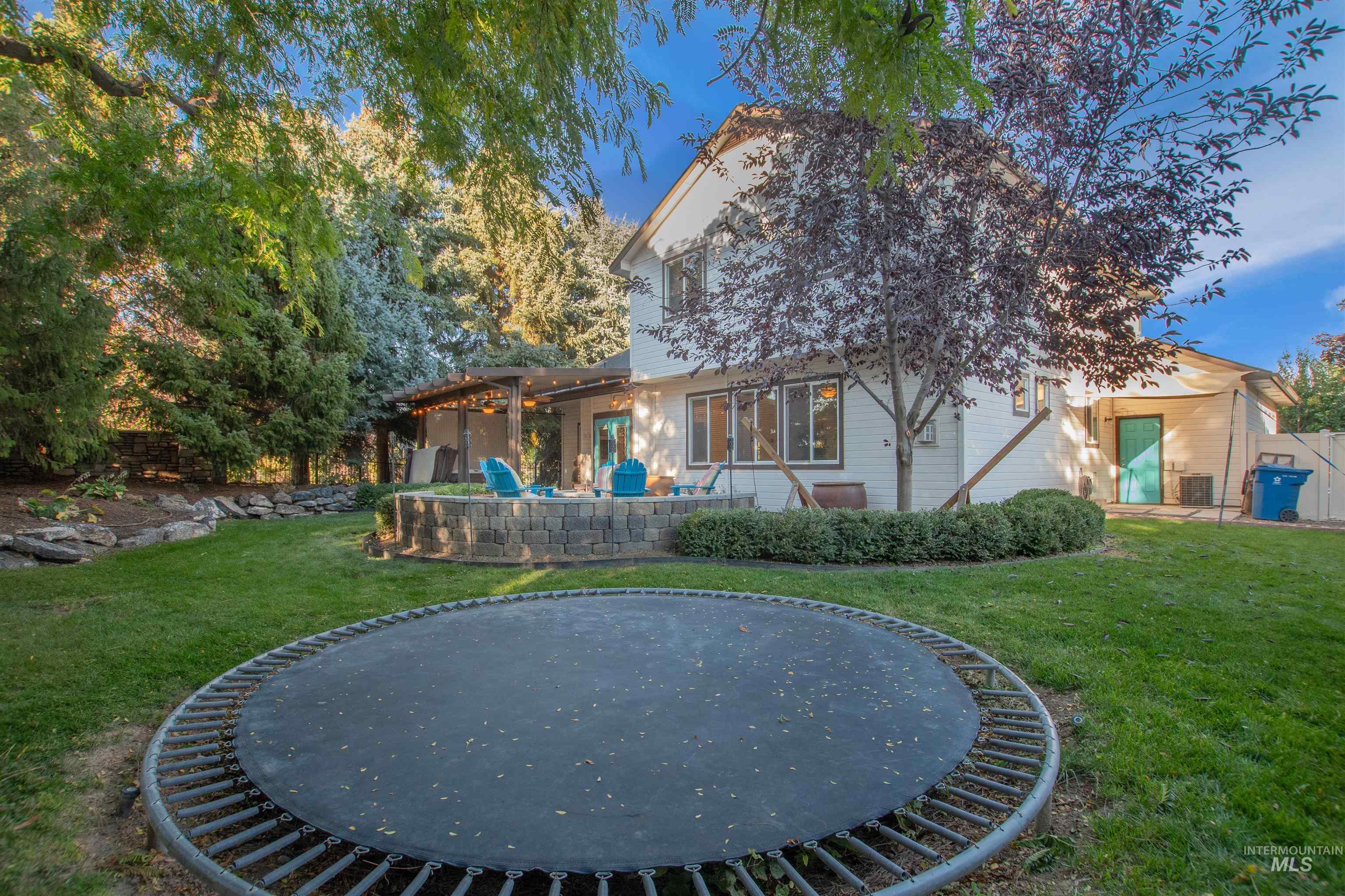 Rear view of house featuring a patio area, a yard, and a trampoline