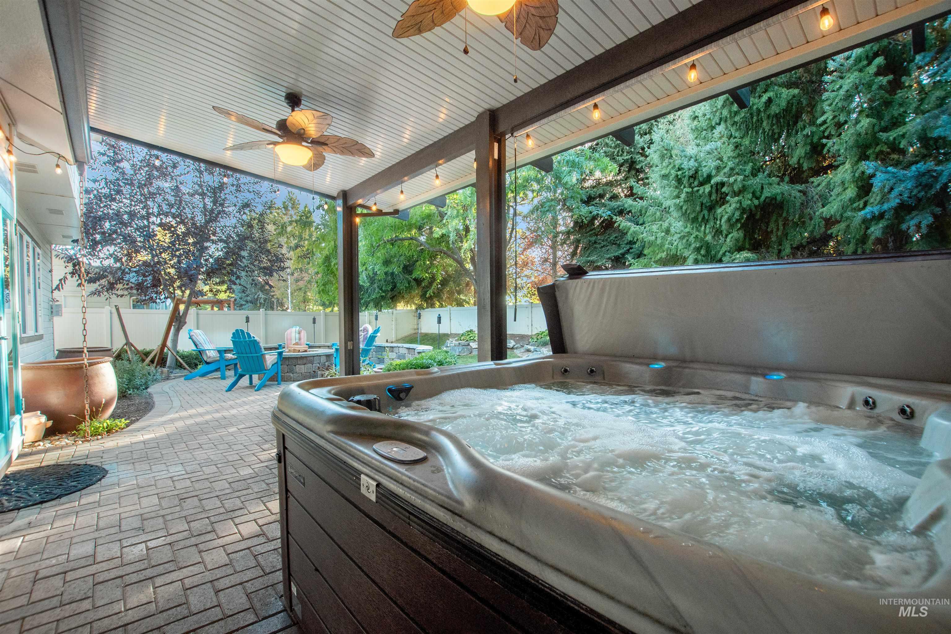 Fenced backyard with a patio area, a hot tub, and a ceiling fan