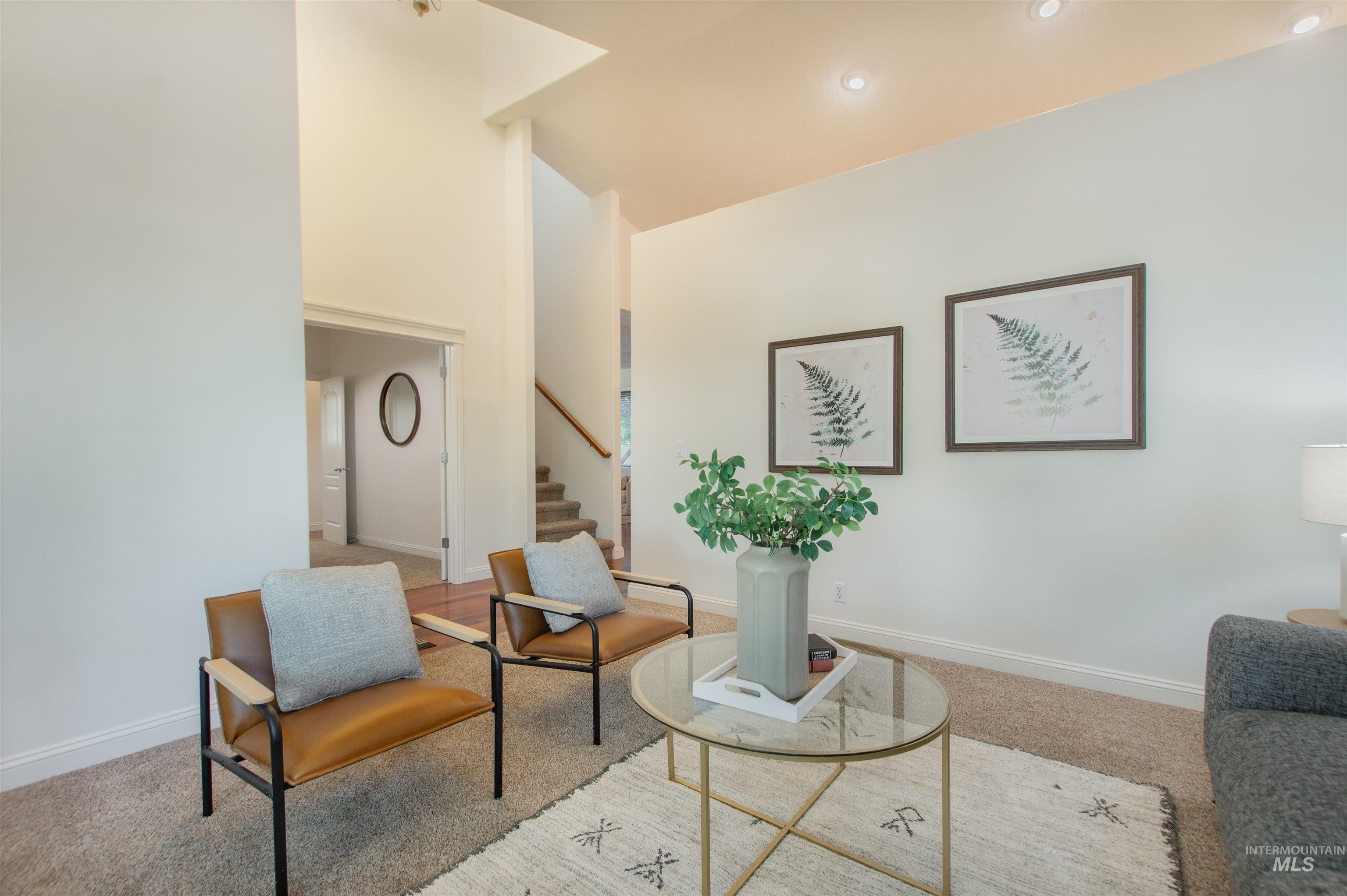 Living area with carpet flooring, stairs, recessed lighting, and a high ceiling