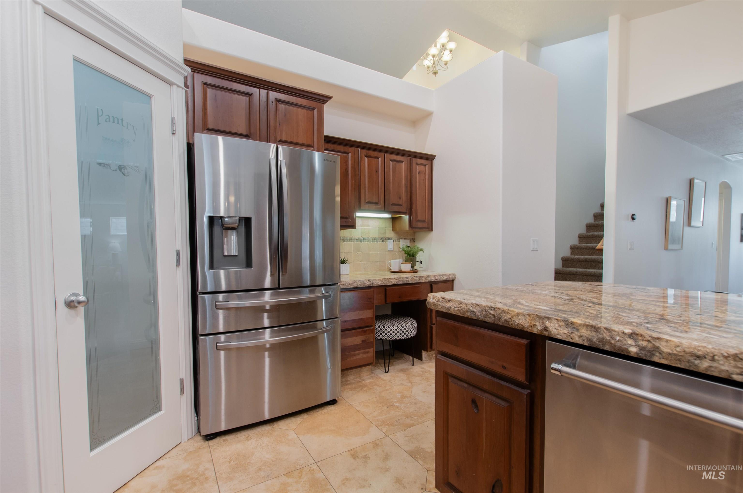 Kitchen with light stone countertops, appliances with stainless steel finishes, decorative backsplash, and light tile patterned floors