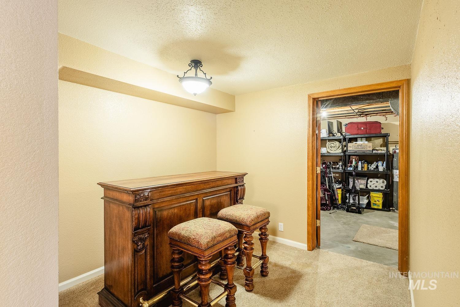 Office space with a textured ceiling, light colored carpet, and a textured wall