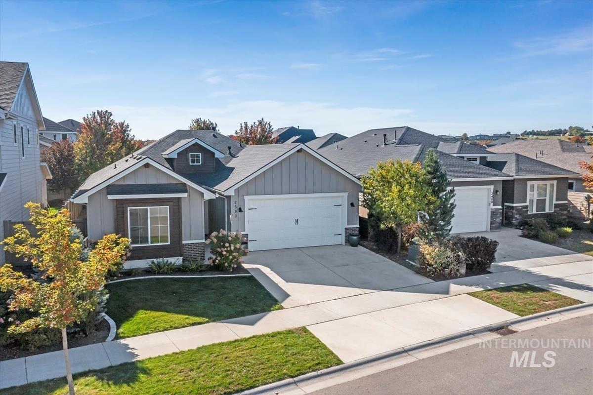 View of front facade featuring board and batten siding, driveway, an attached garage, a residential view, and a front lawn