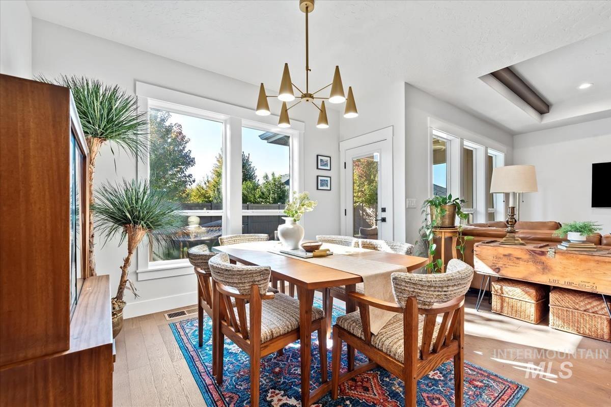 Dining space featuring hardwood / wood-style floors, a chandelier, and a tray ceiling
