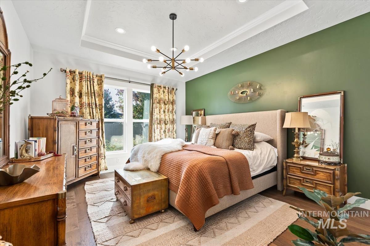 Bedroom with a tray ceiling, wood finished floors, a chandelier, and recessed lighting